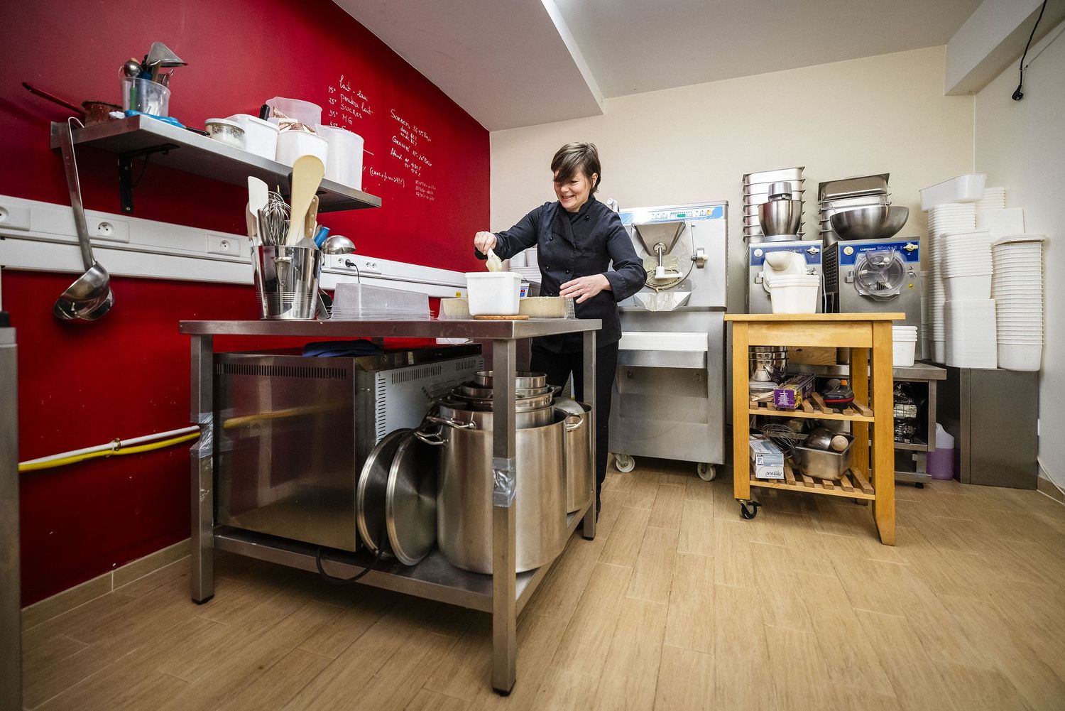 Professional kitchen workspace with stainless steel prep tables and red accent wall in a commercial setting.Claire Bourguin Bourgain Bourgoi