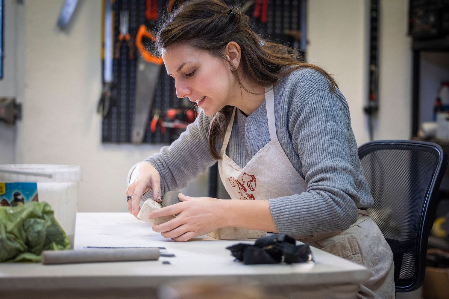 Artist working on detailed project at desk in creative studio space.Claire Bourguin Bourgain Bourgoin Bourquin - Photographe Bruxelles Belgi