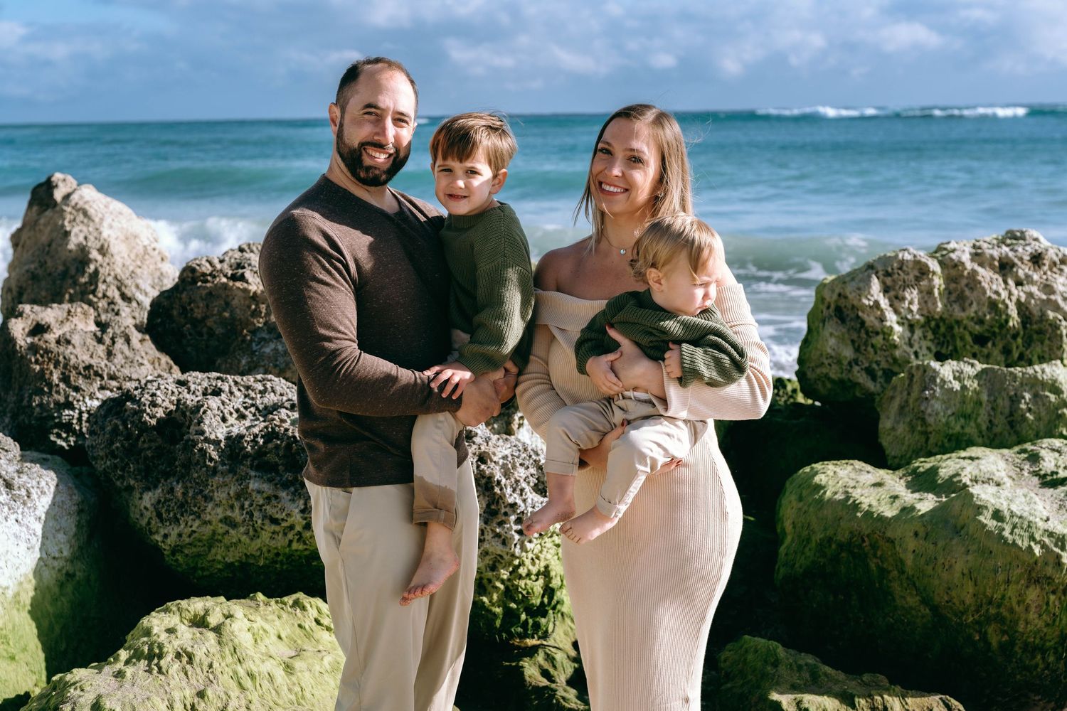 Family sharing tender moments together on a rocky beach overlook.