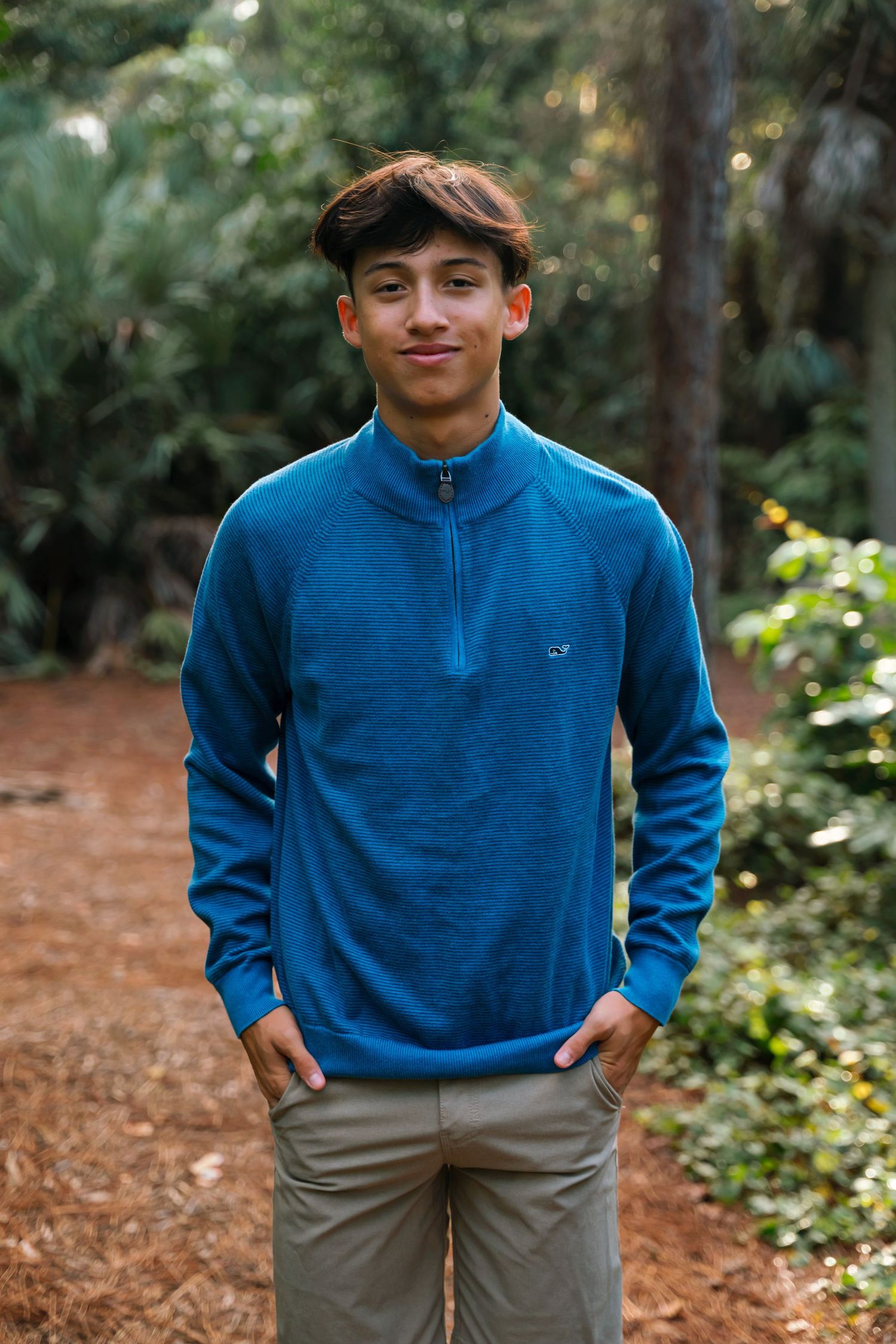 Person wearing blue quarter-zip pullover and khaki pants posing outdoors.