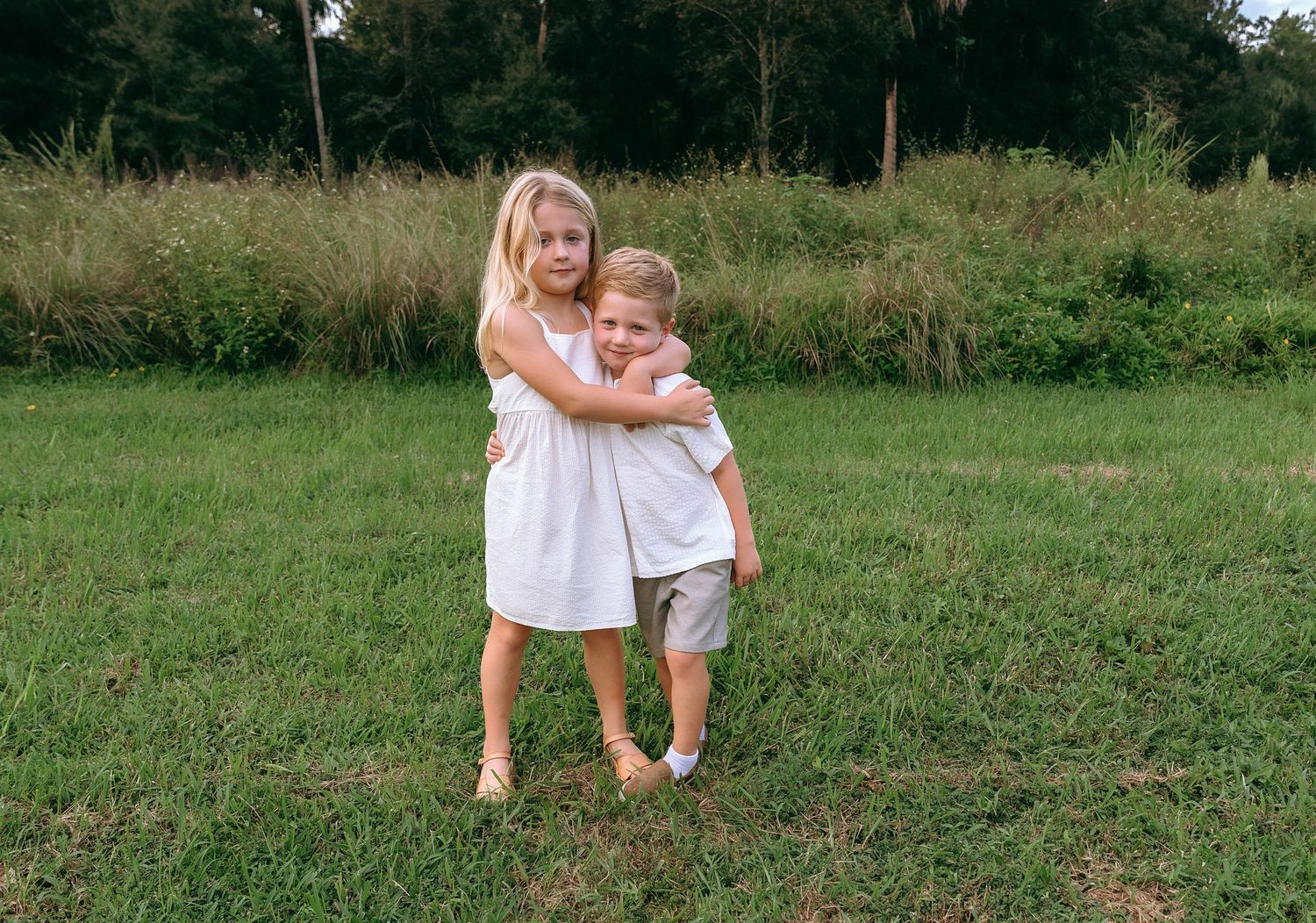 Playful outdoor scene with people in white clothing running on green grass.