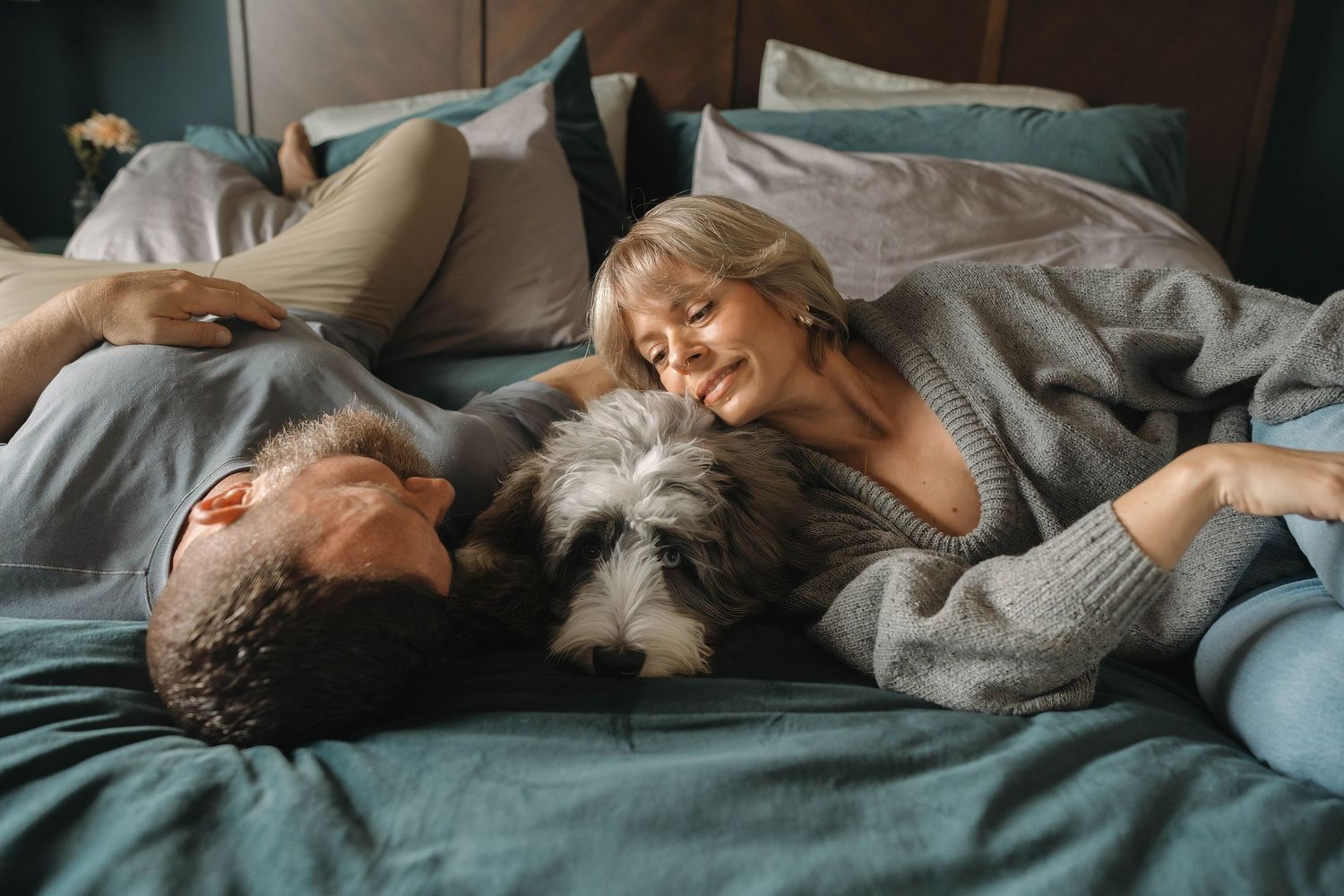 A relaxed moment on bed with a furry dog joining the cuddle session.