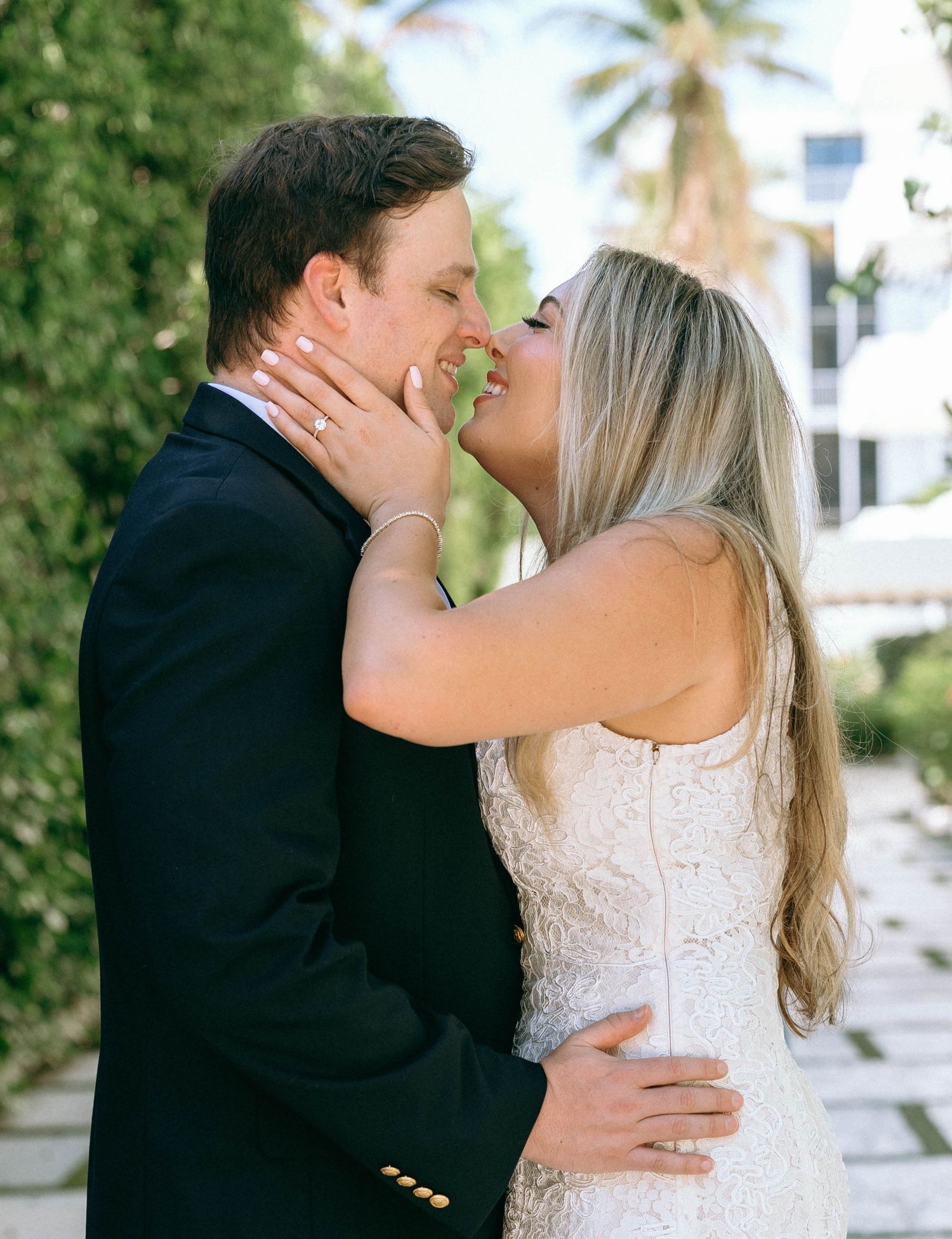 Bride and groom sharing a romantic kiss in a lush garden setting on their wedding day.