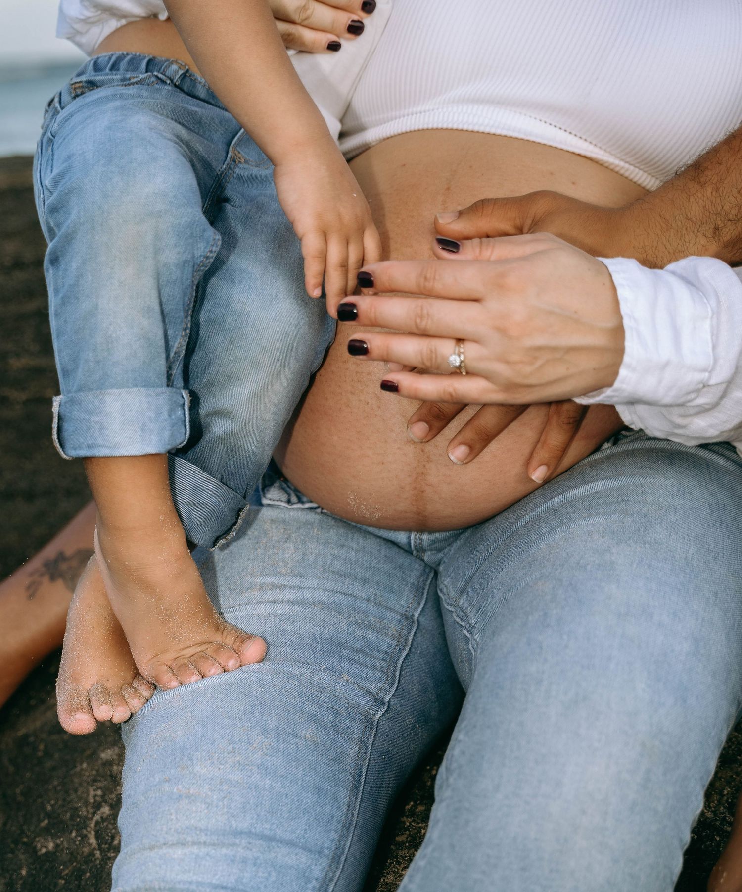 Close-up series of tender moments showing hands resting on denim-clad legs and a pregnant belly.