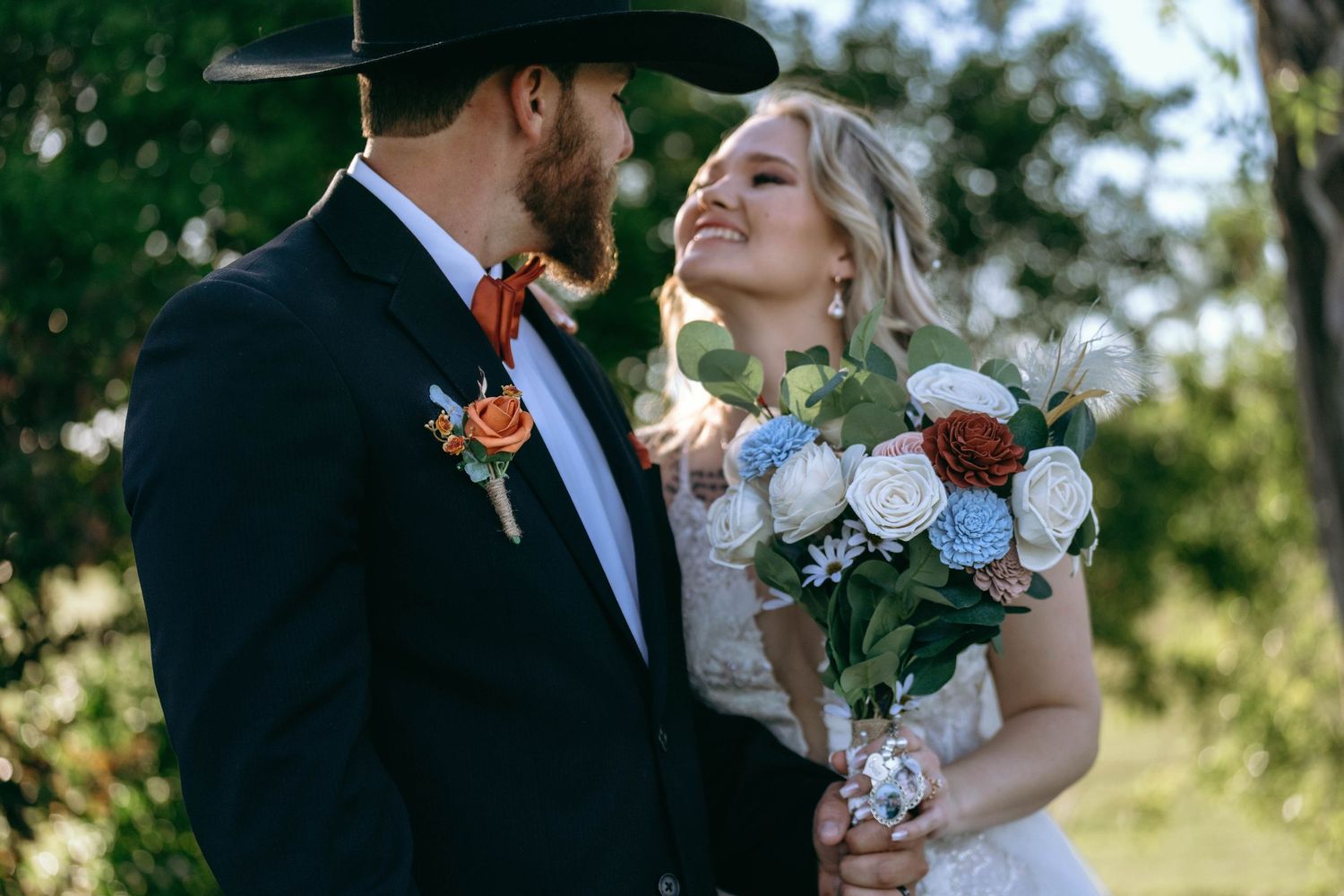 Wedding couple shares intimate moments outdoors with the bride holding a colorful bouquet.