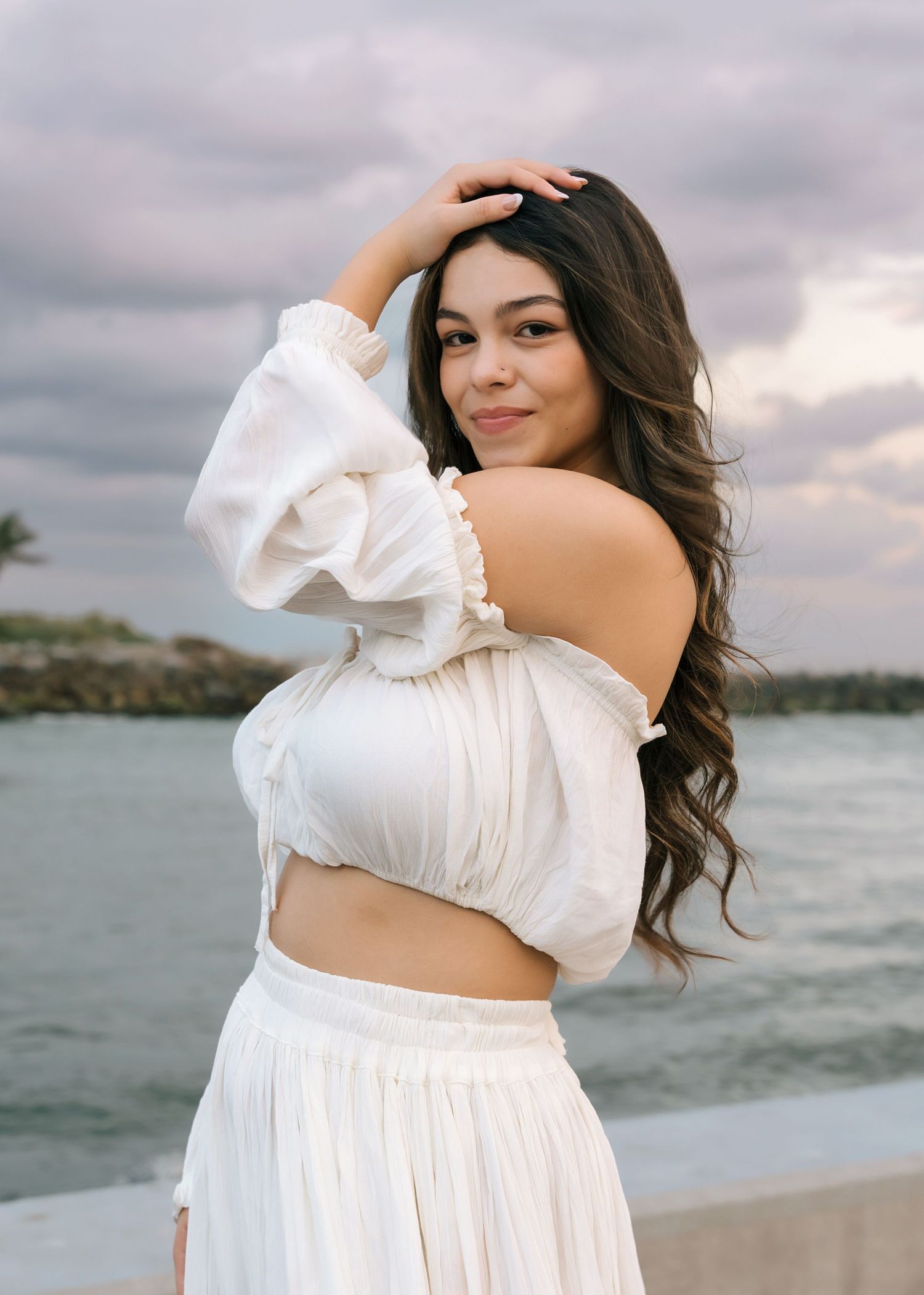 A white two-piece outfit with puffy sleeves photographed by the ocean.