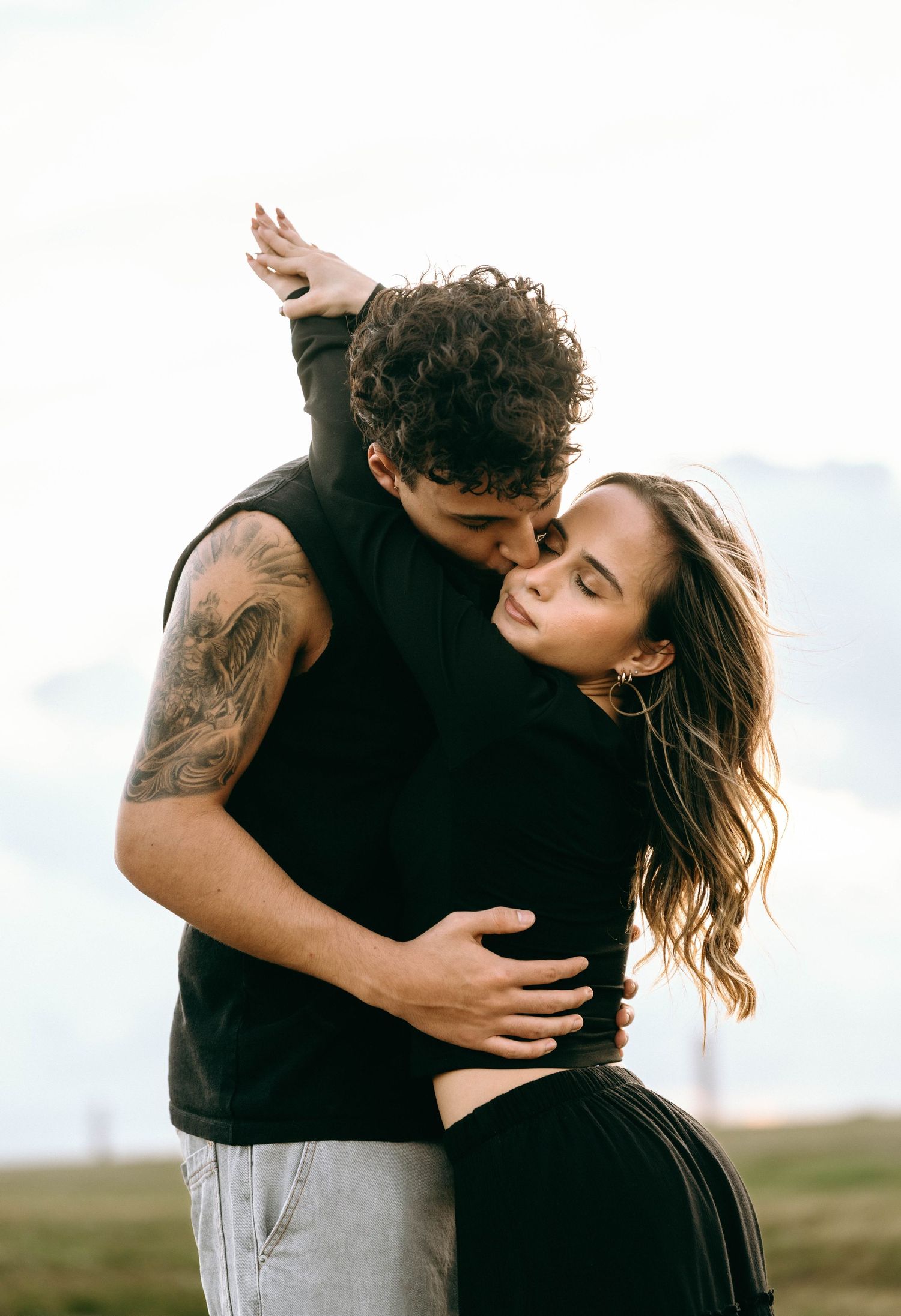 Intimate moment between couple sharing tender embrace in outdoor setting.