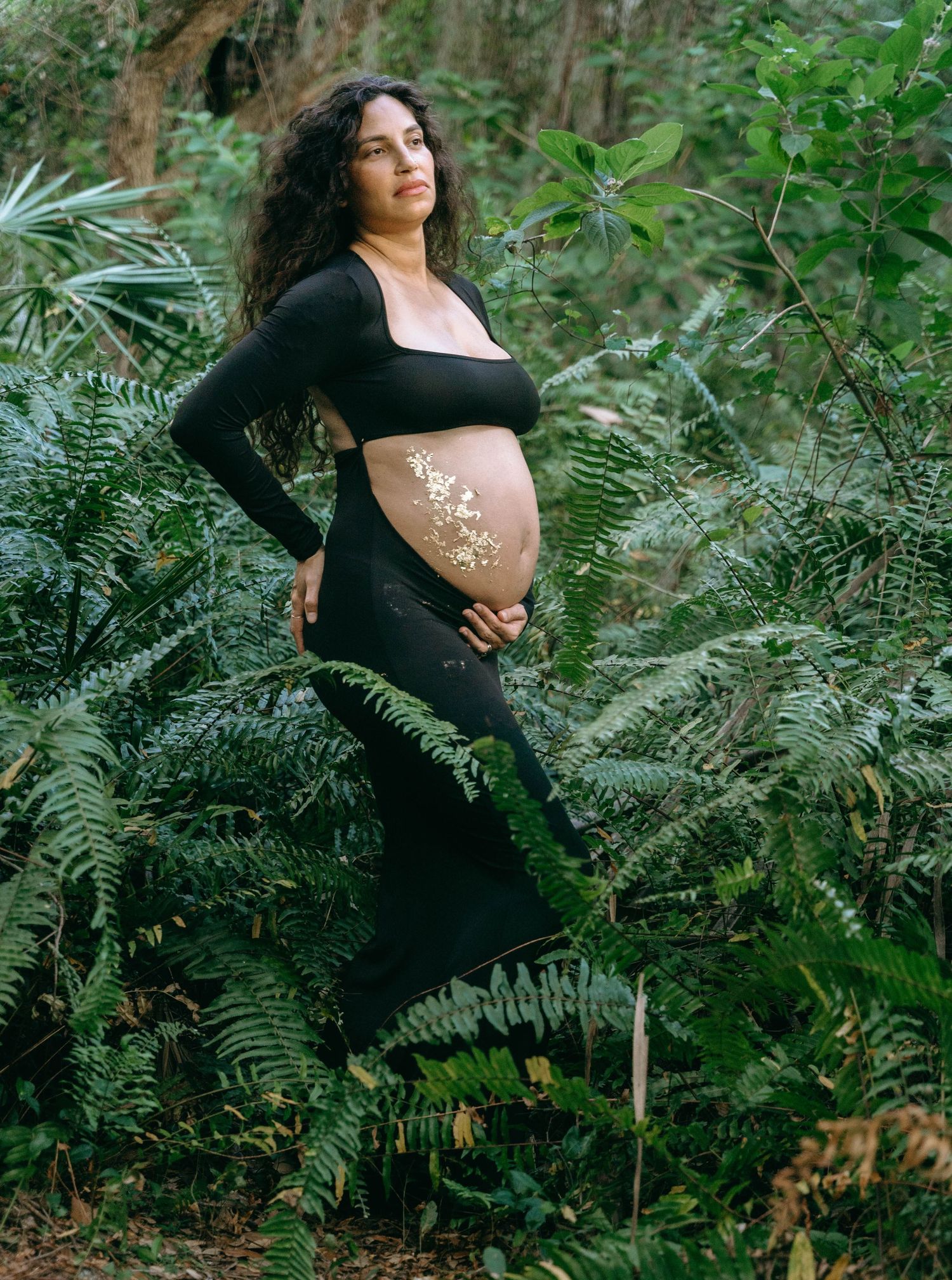 A maternity portrait in black attire against a backdrop of wild ferns.