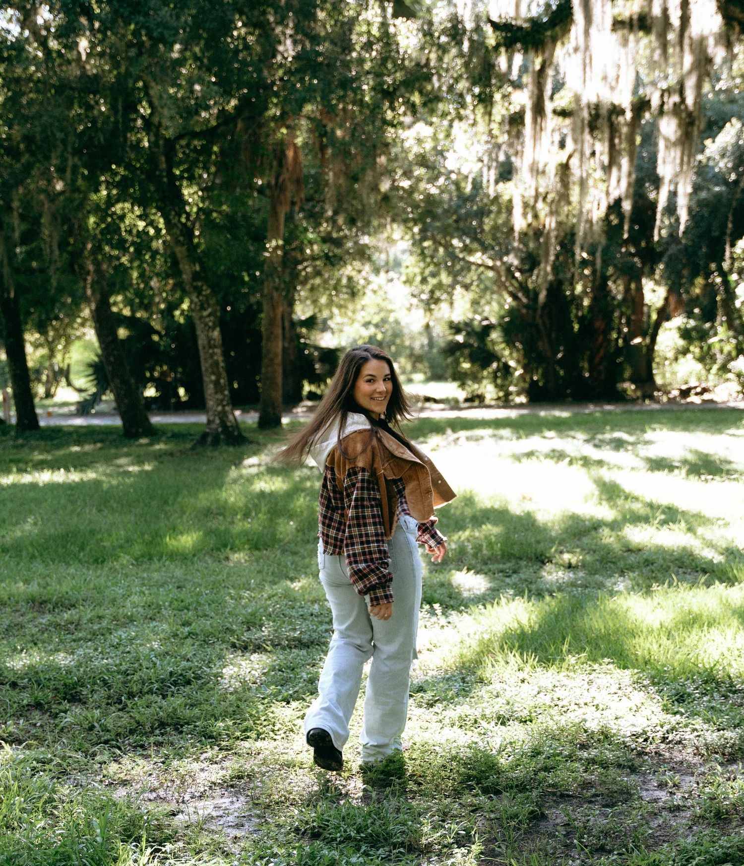 Figure in casual attire moves energetically through a sunlit wooded park area.