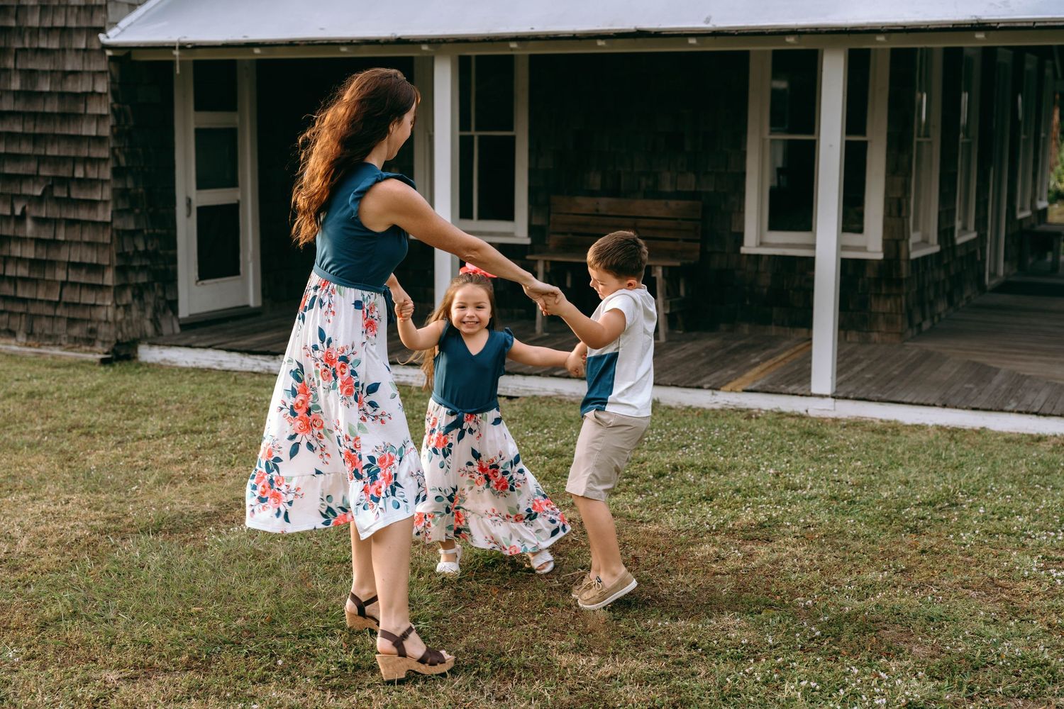 People enjoying outdoor activities on the lawn of a traditional shingled home.