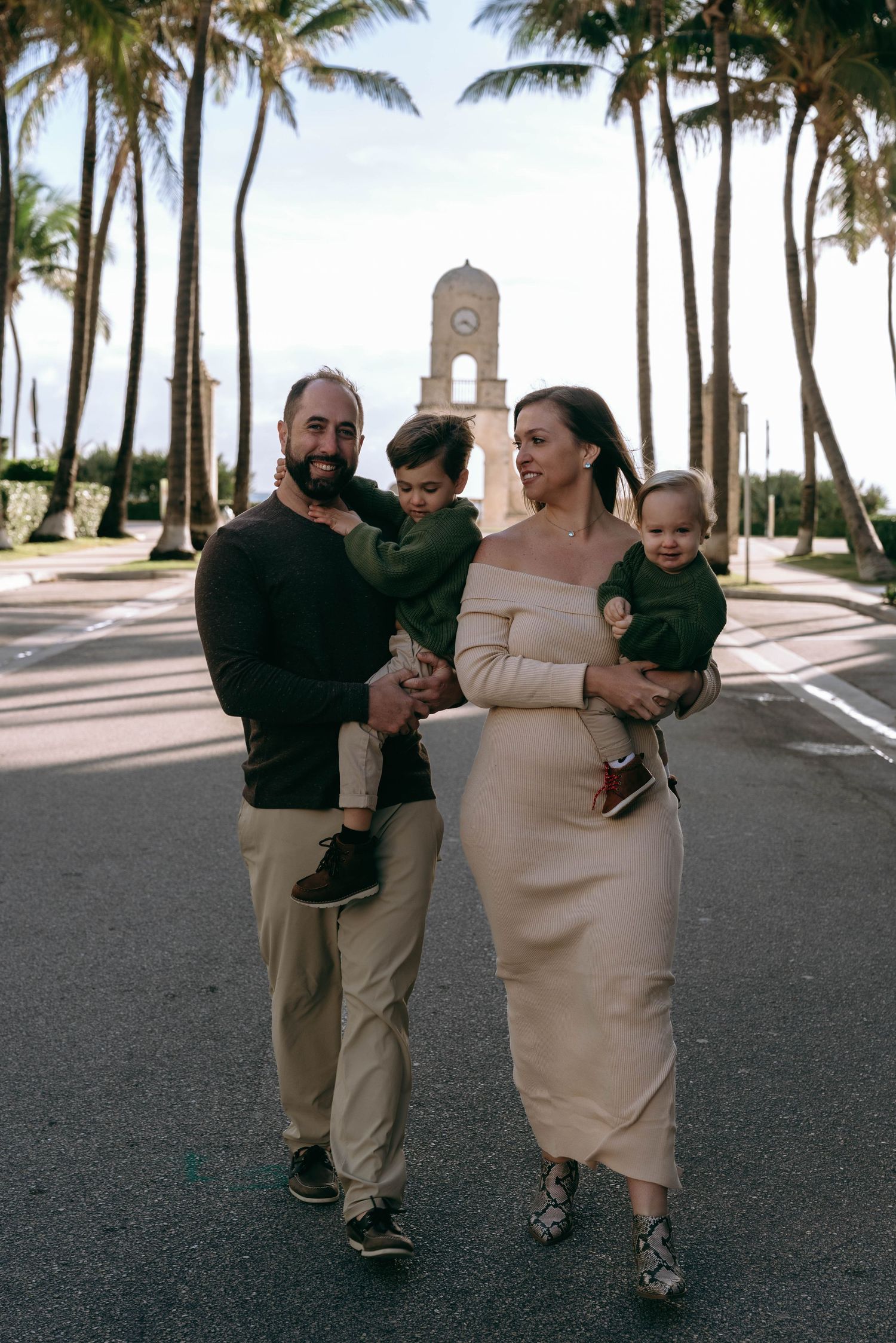 Family walking together along palm tree-lined path.