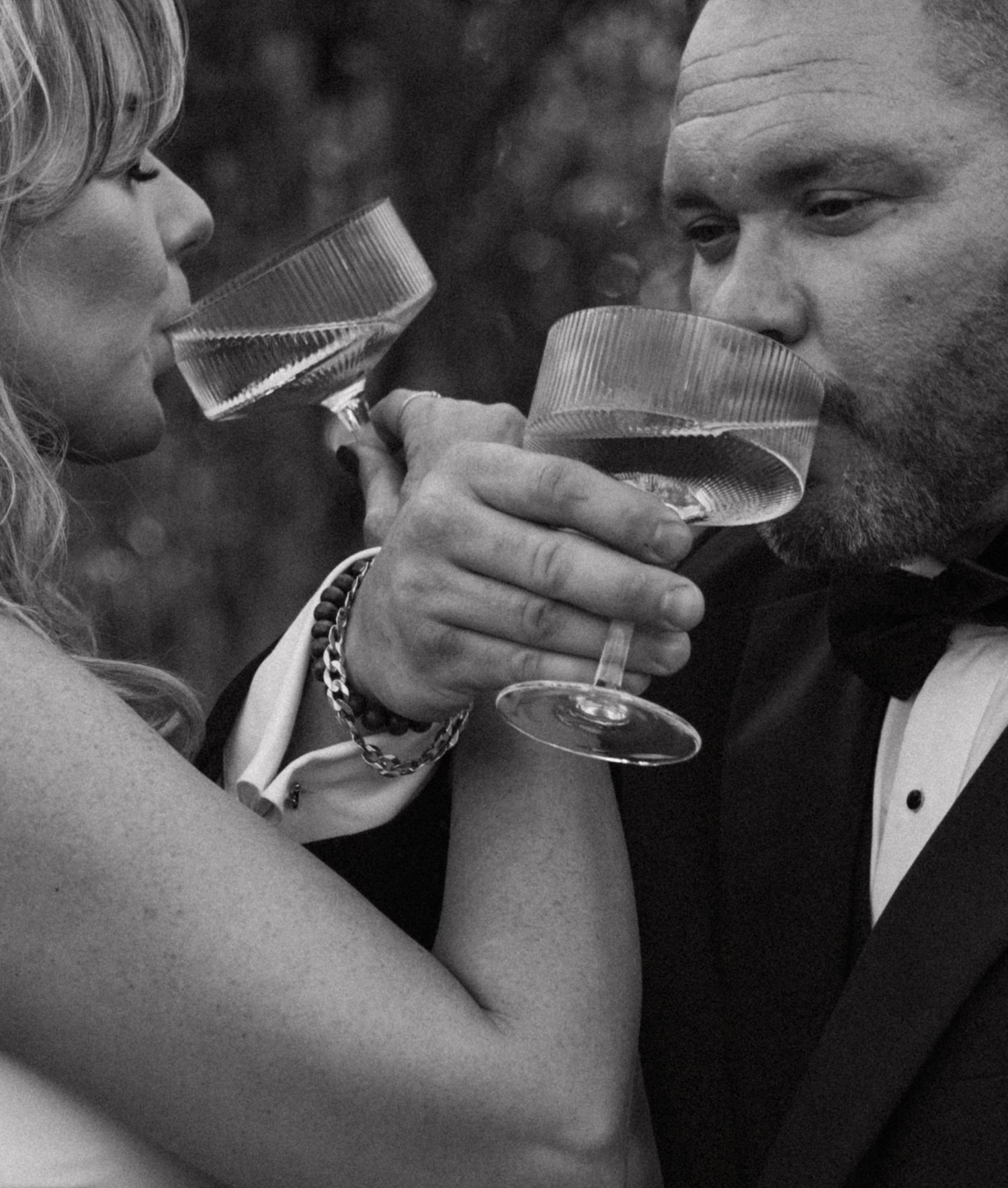 Black and white sequence of newlyweds sharing champagne during their wedding celebration.