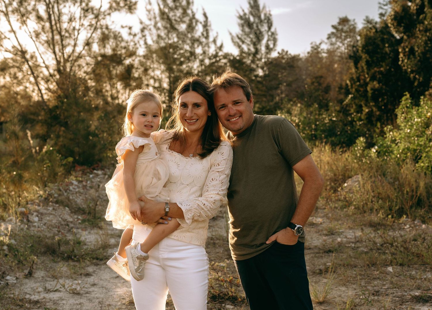 Family photoshoot captured in warm evening light among natural scenery.