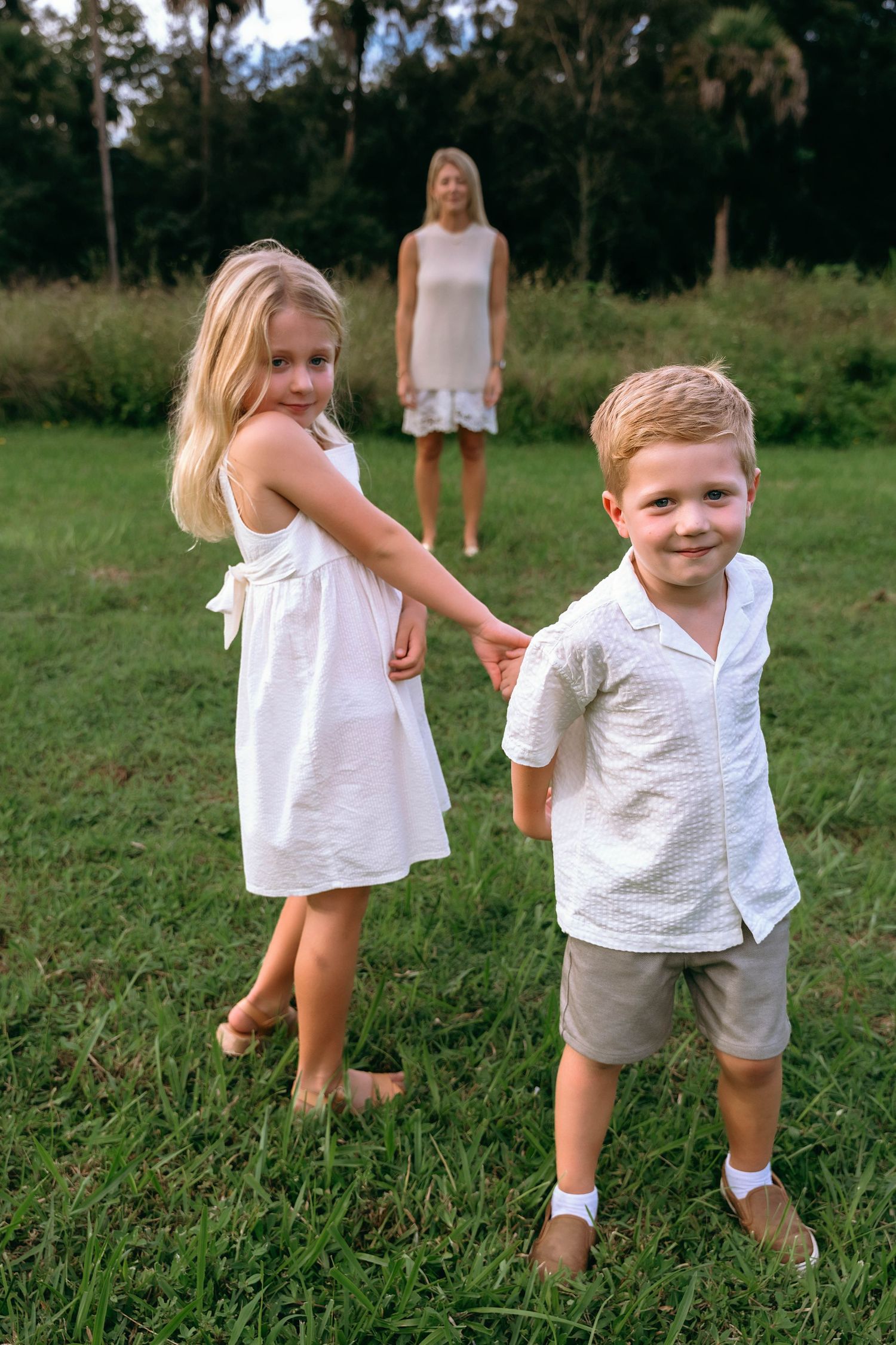 Group playing and running on grass in coordinated white summer outfits.