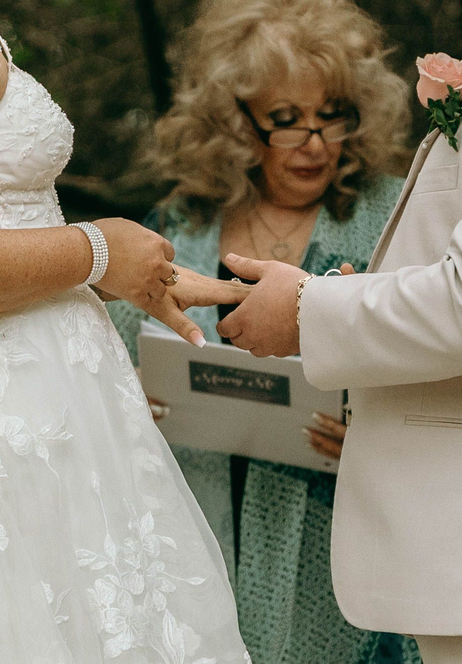 A couple signs their marriage license during a wedding ceremony while wearing formal attire.