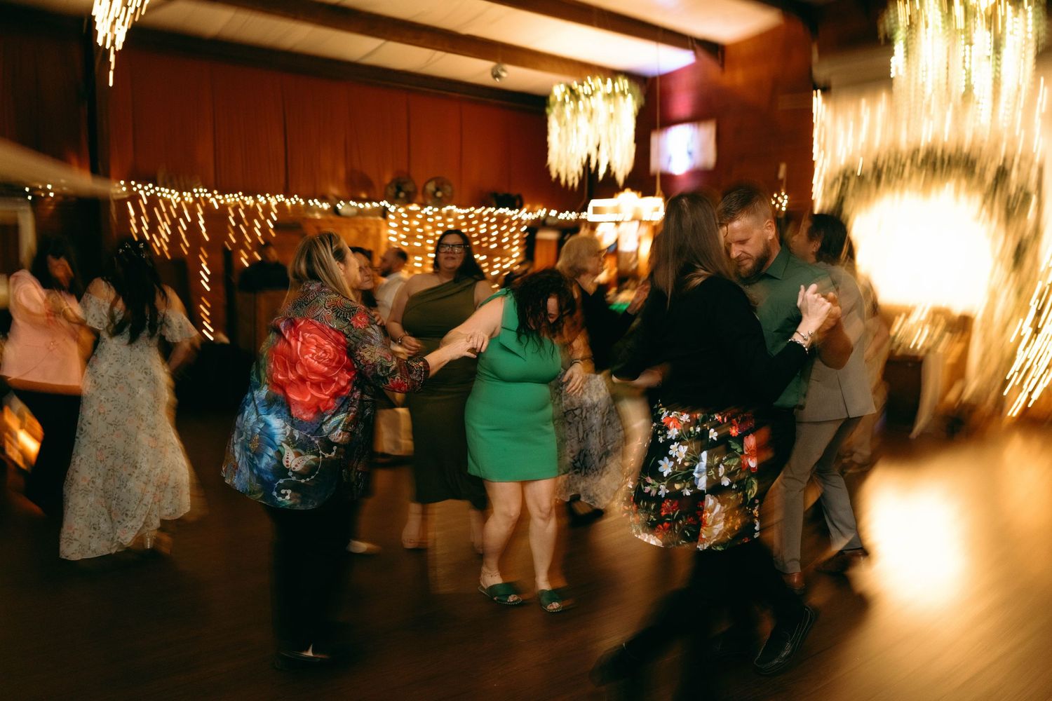 Blurred dance floor scene at a wedding reception with warm lighting and guests celebrating.