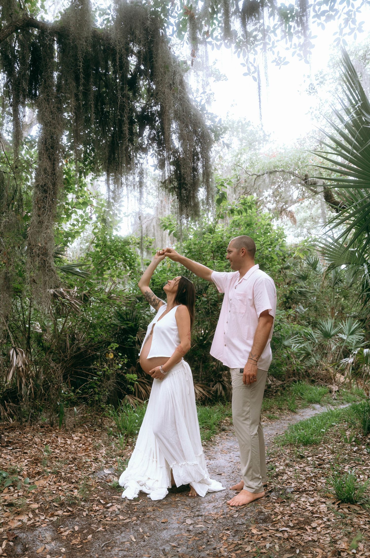 A maternity dance pose photo in a dreamy forest setting with Spanish moss.