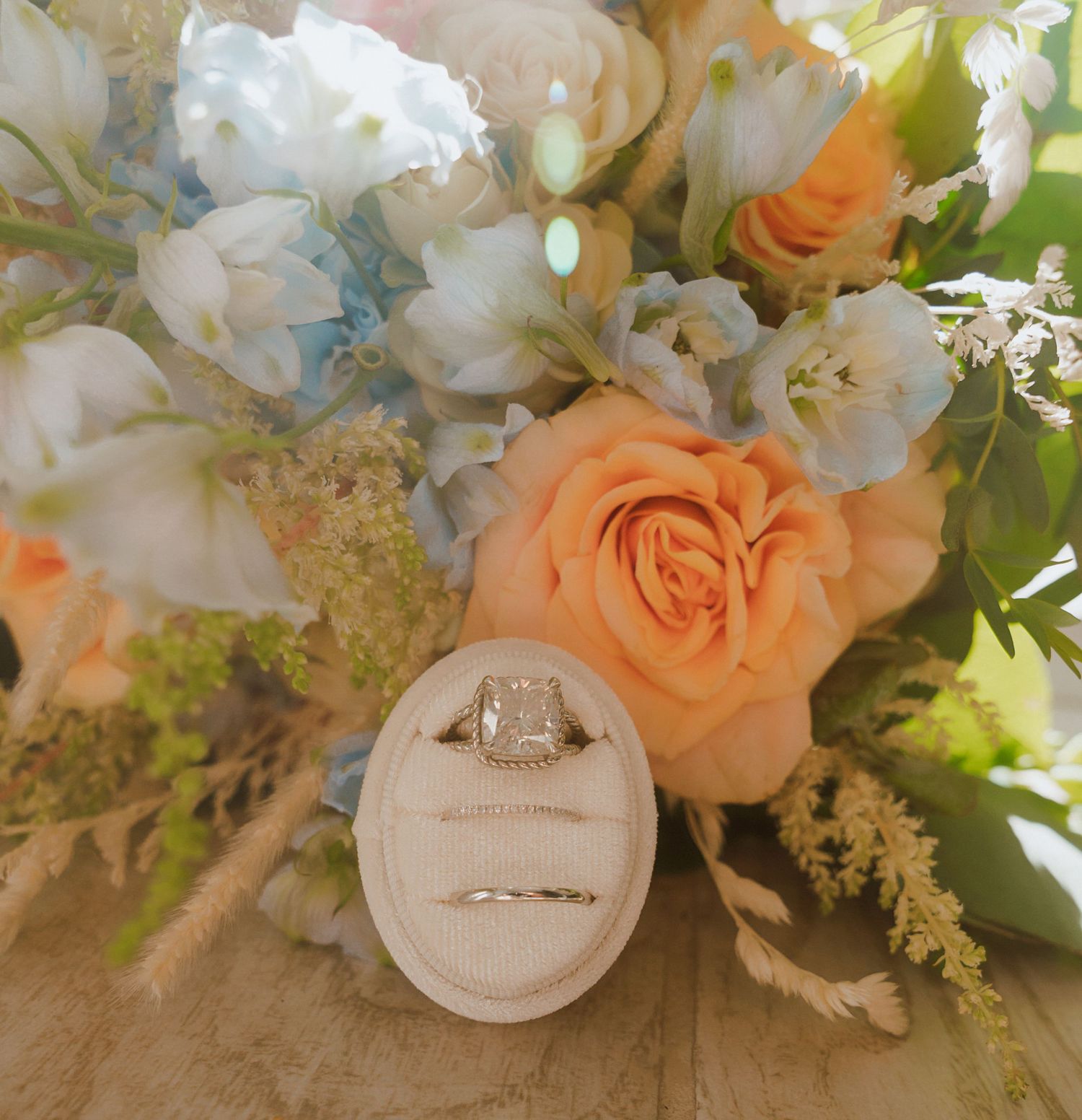 Peach and white floral wedding bouquet with engagement ring detail shot.