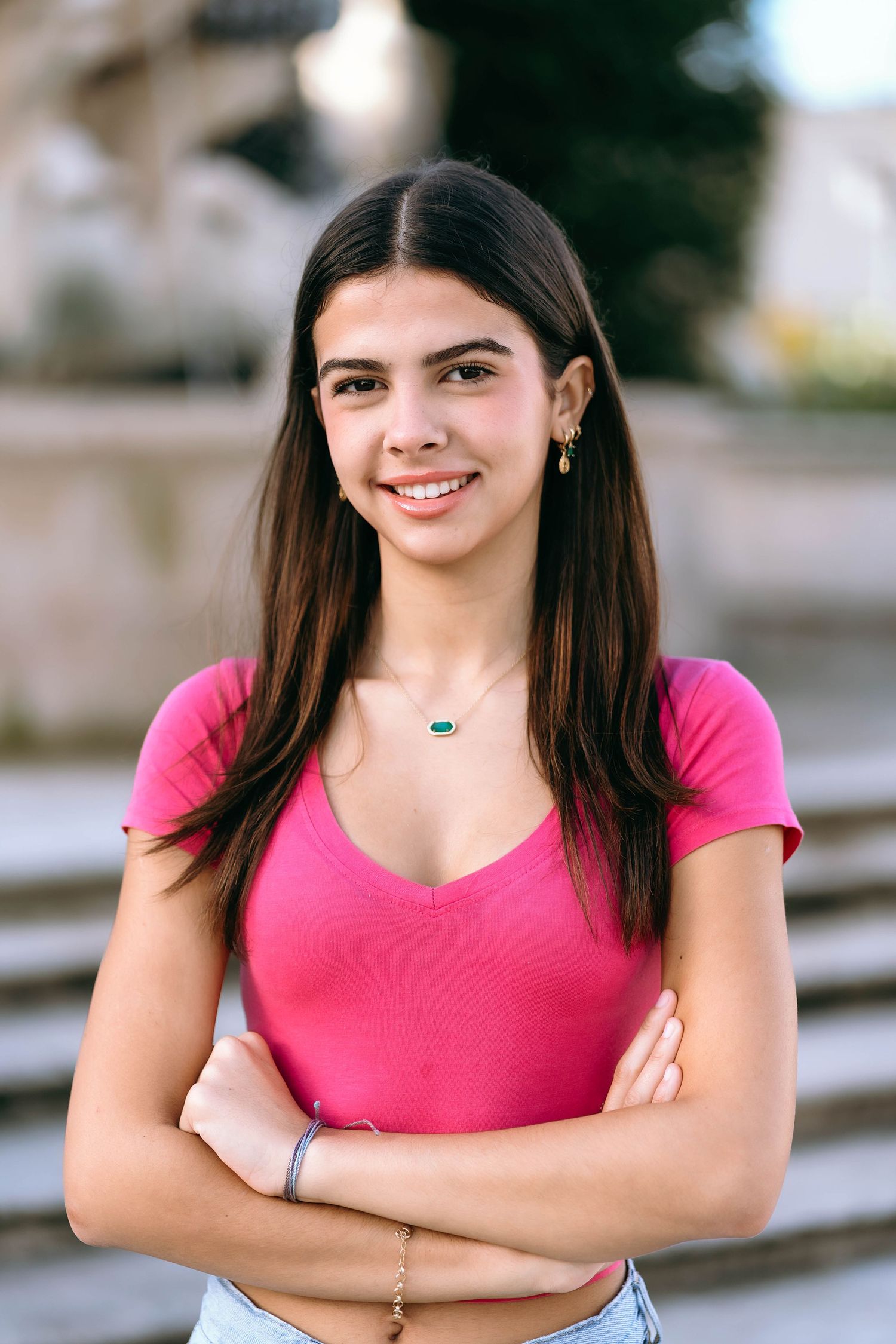 Person in bright pink top poses confidently against neutral background.