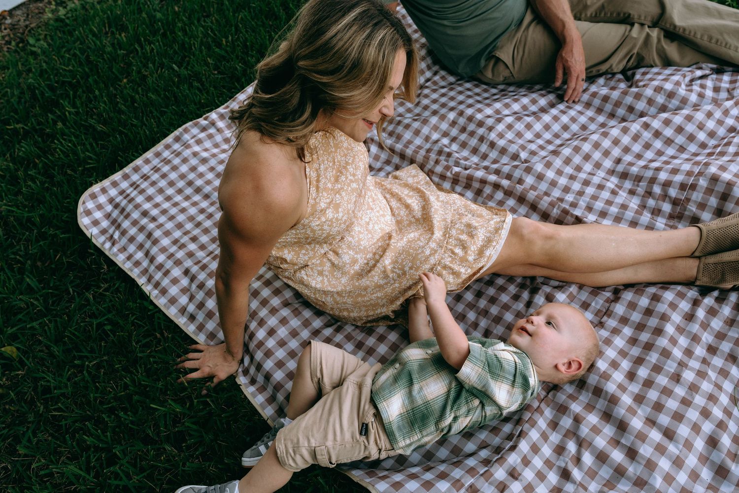 Relaxed outdoor picnic photoshoot on checkered blanket with soft natural lighting.