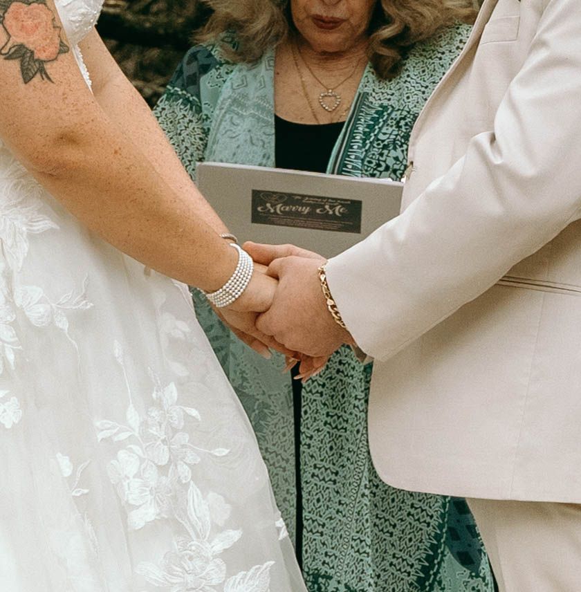 A person in a white top and sage green skirt holds hands with someone wearing a matching sage green outfit.