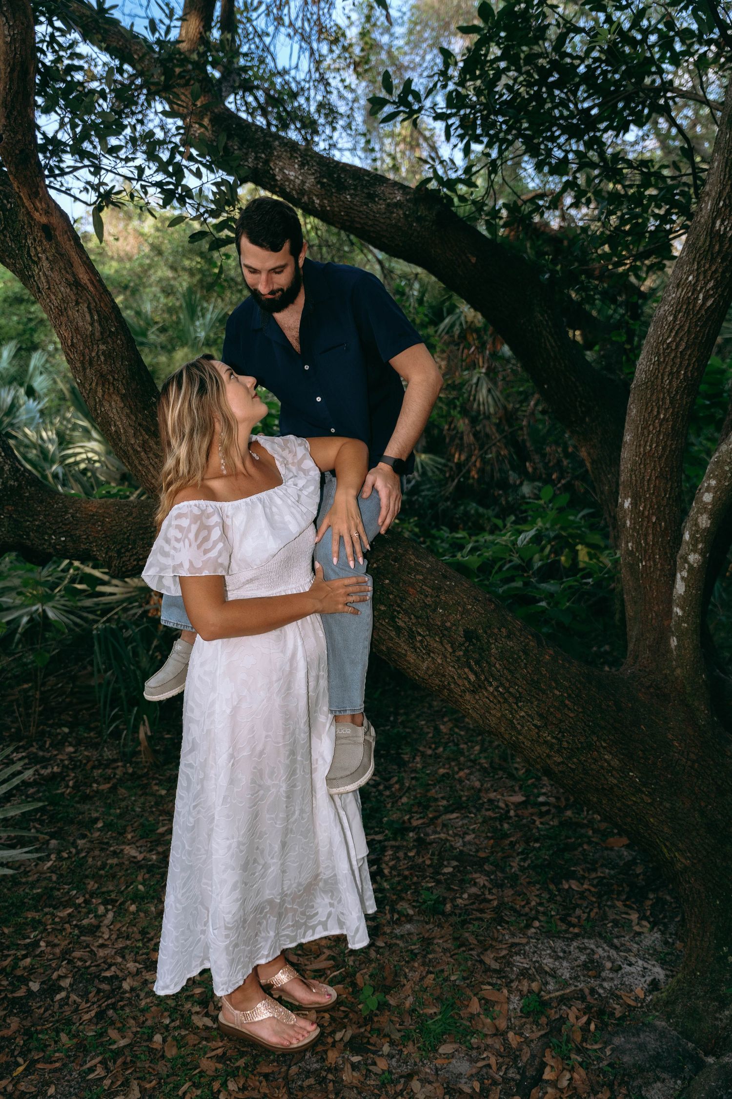 A couple poses together near trees in a natural outdoor setting.