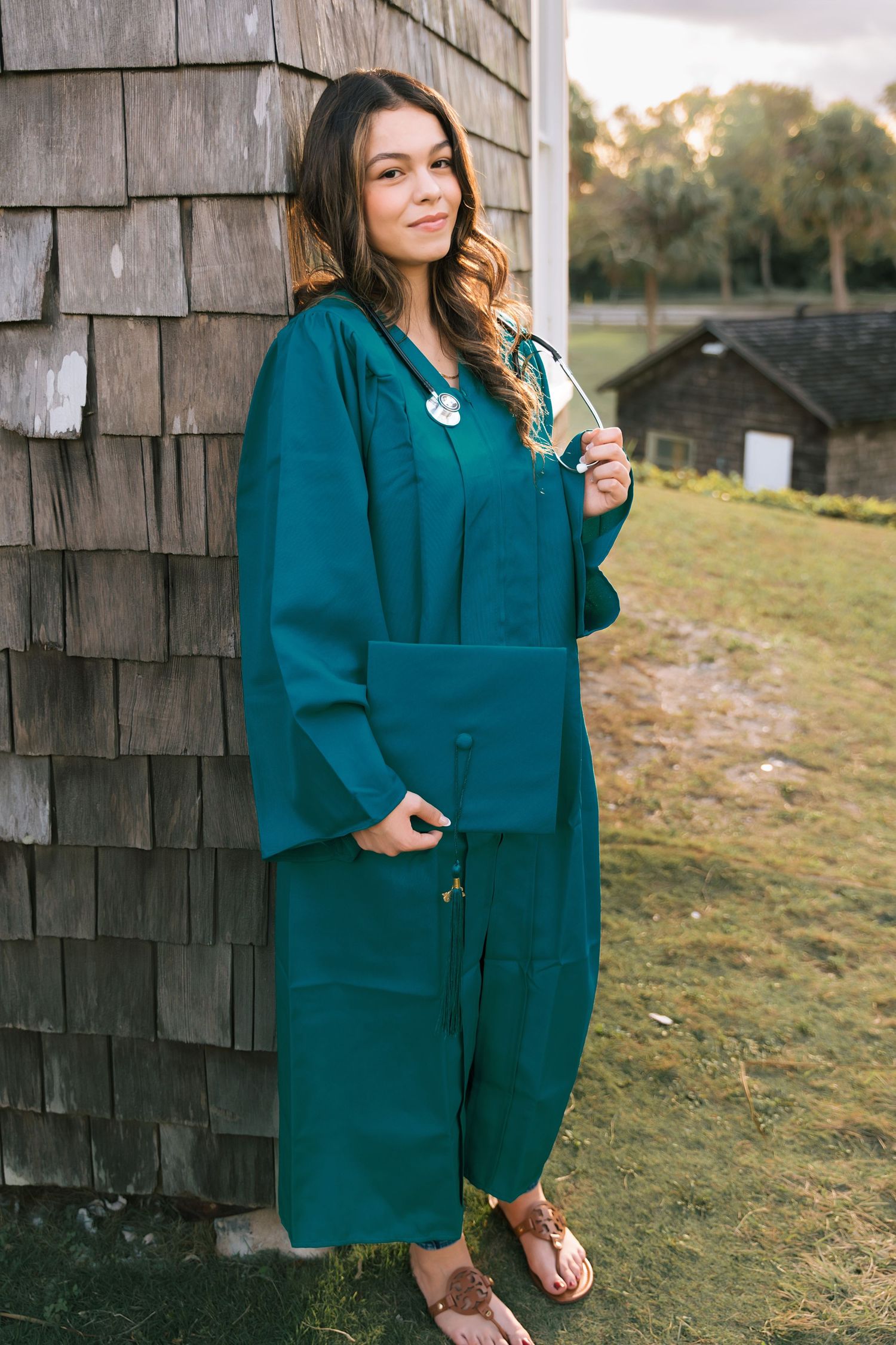 Model wearing teal loungewear set poses against weathered shingle wall outdoors.