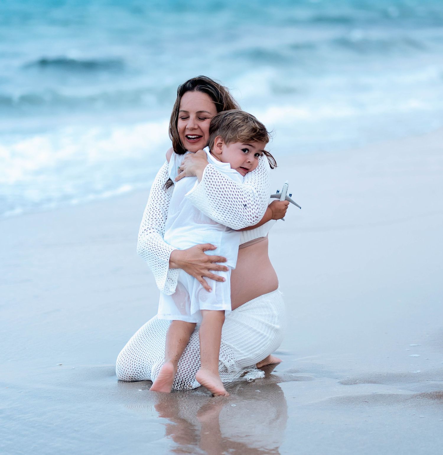 A joyful moment captured at the beach with people playing in the gentle waves at sunset.