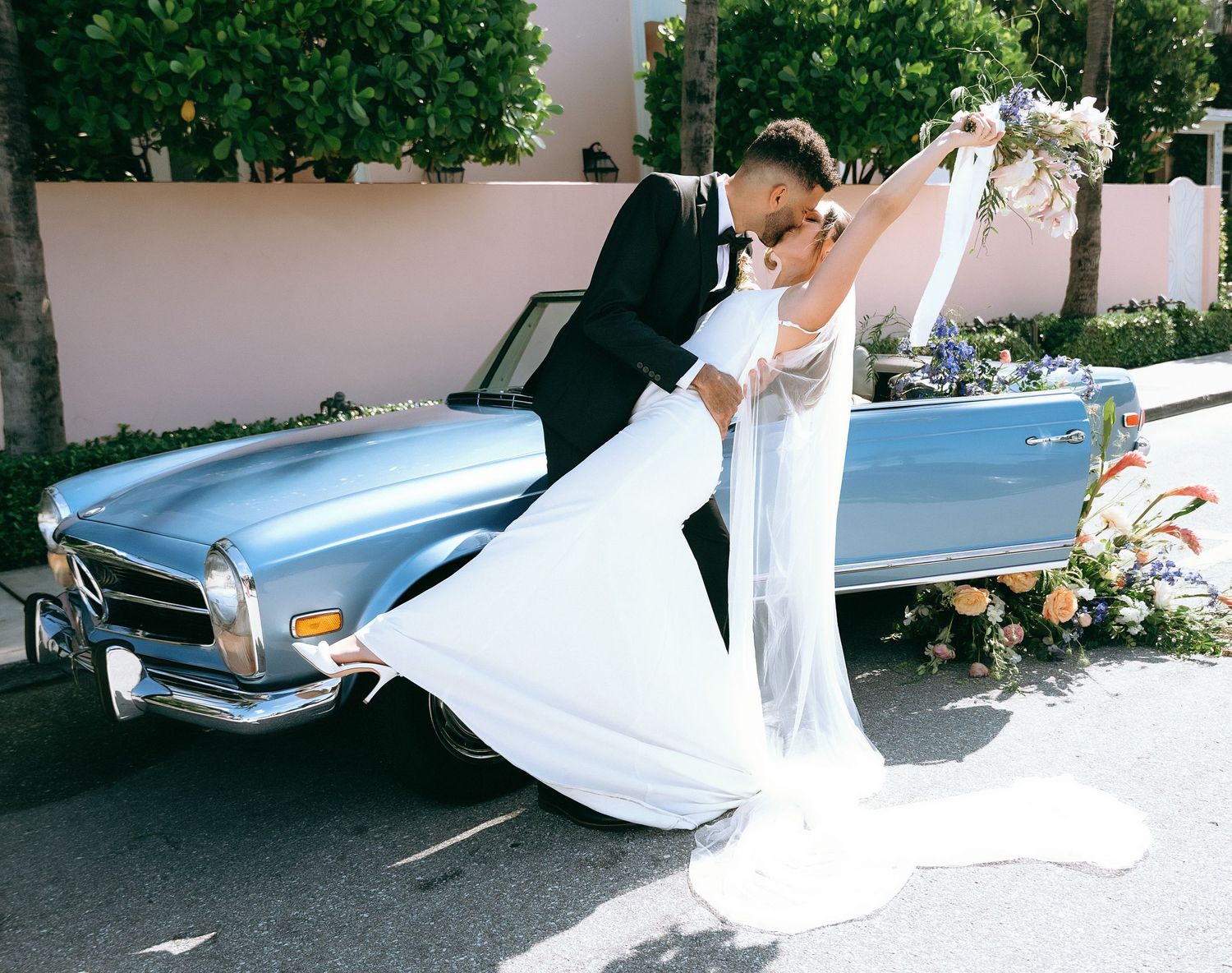 Wedding couple posing together near vintage car outdoors.