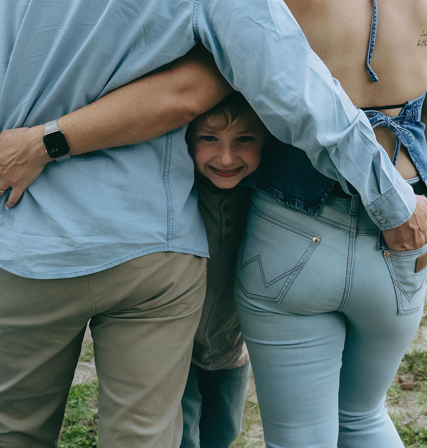 Close-up view of people wearing casual clothing standing together outdoors.