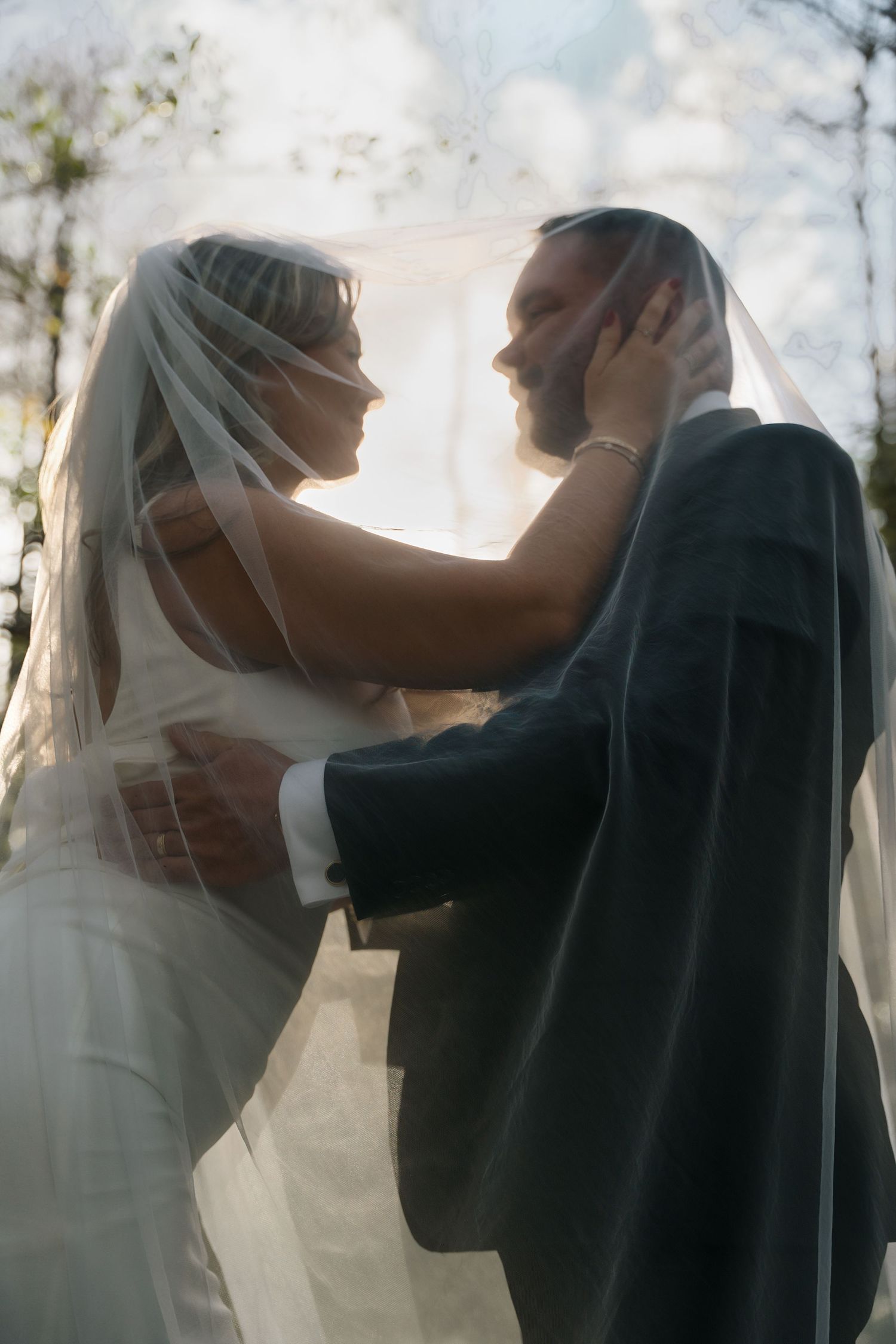 Ethereal backlit wedding portraits showing romantic moments through a flowing veil.