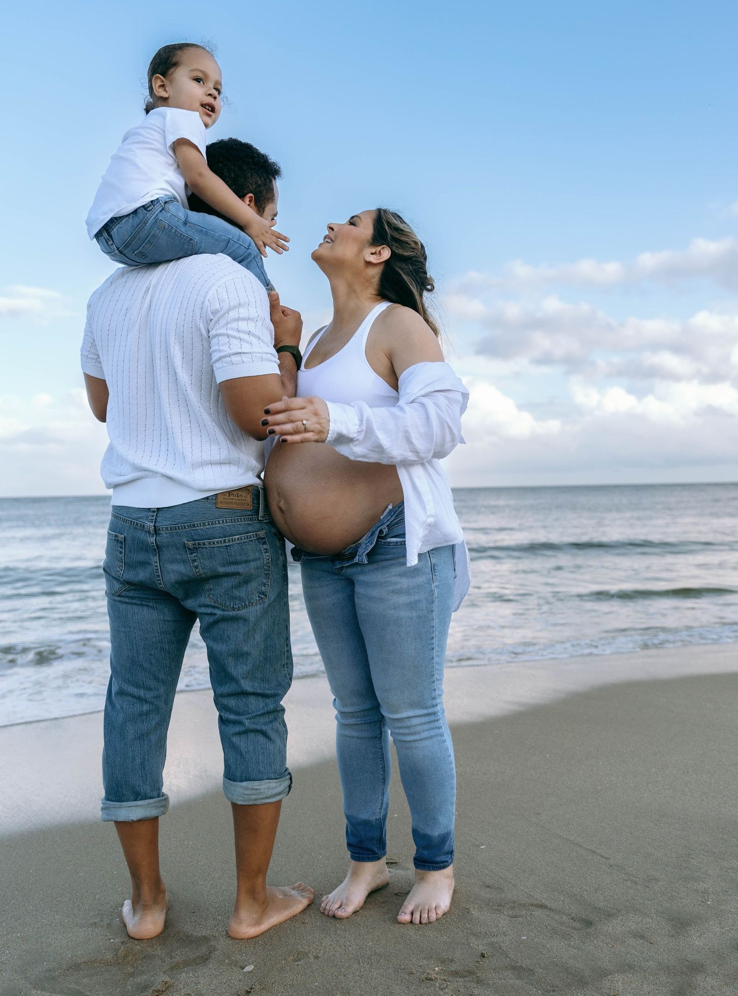 Couple embracing on a sandy beach during sunset maternity photography session.