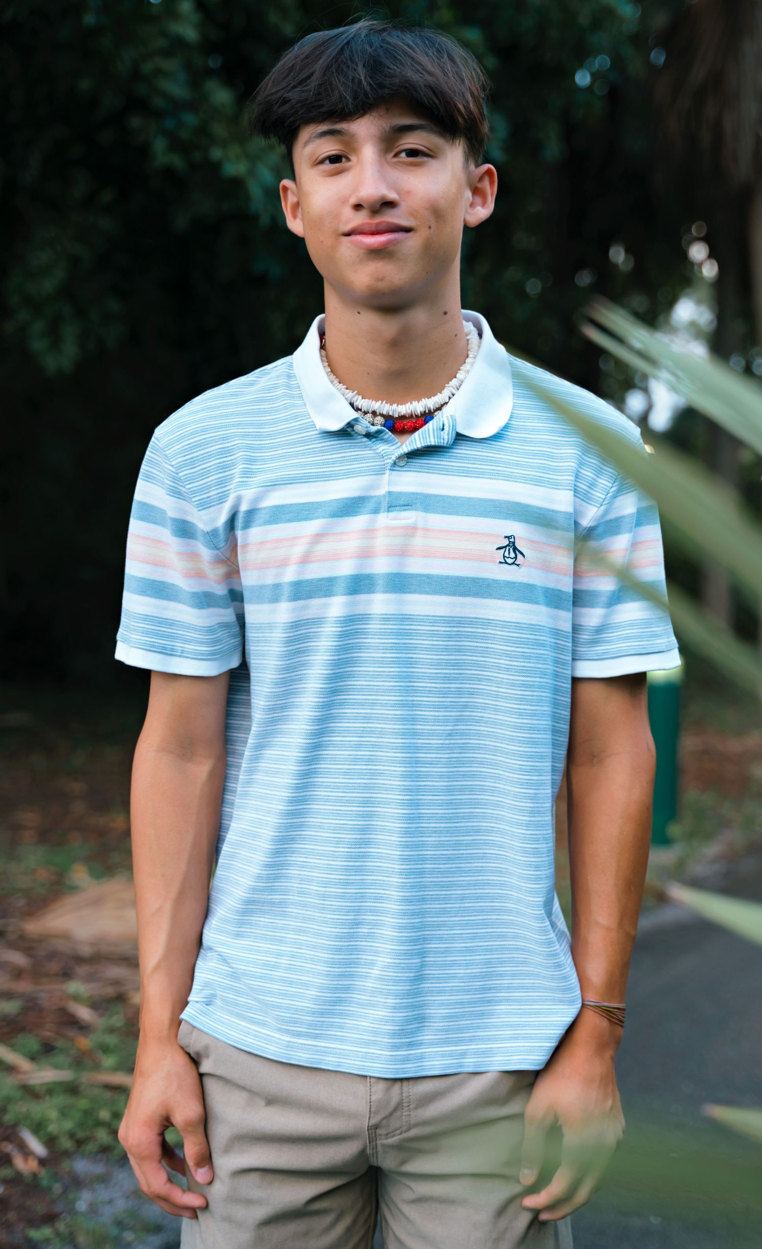 Person wearing light blue striped polo shirt and khaki pants outdoors.