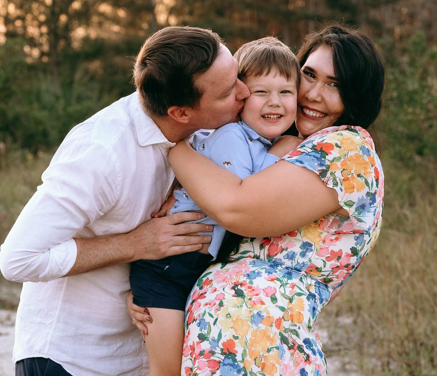 A loving family embraces and shares affectionate moments in an outdoor setting at golden hour.