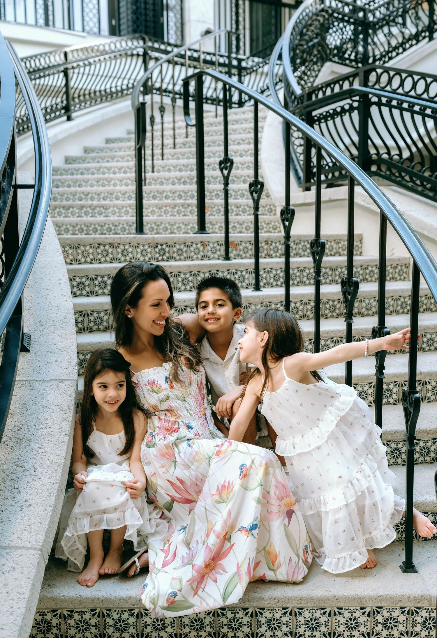 A woman and three children sit together on ornate tiled steps, wearing floral and white dresses. Worth Avenue, Palm Beach, FL