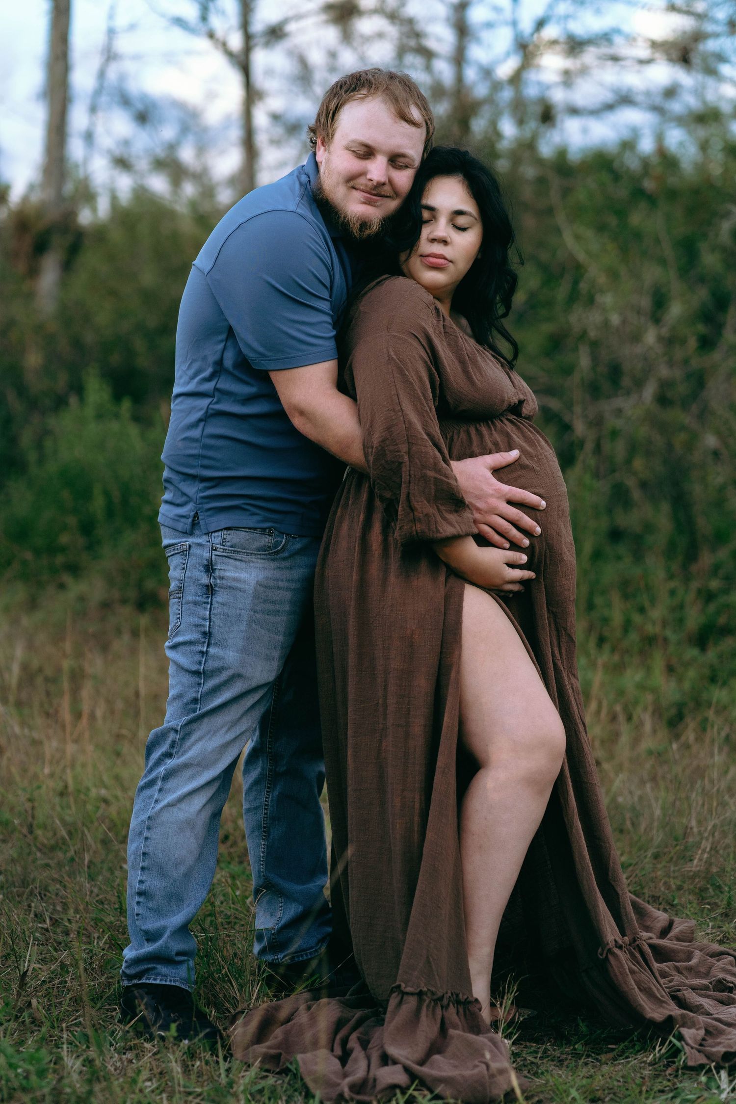 Intimate maternity photoshoot in a natural outdoor setting with a brown wrap dress.