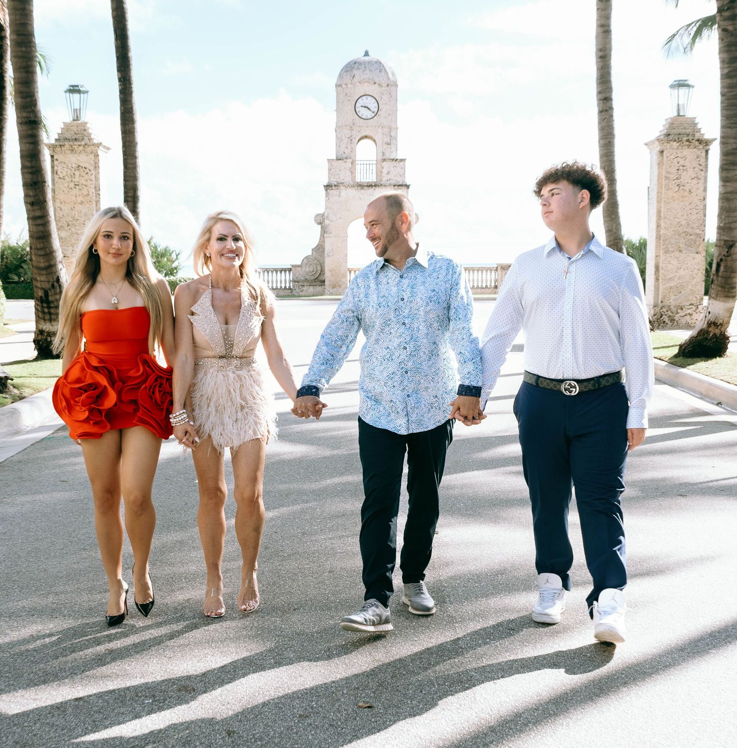 Family walking together on a palm-lined path with decorative stone architecture.