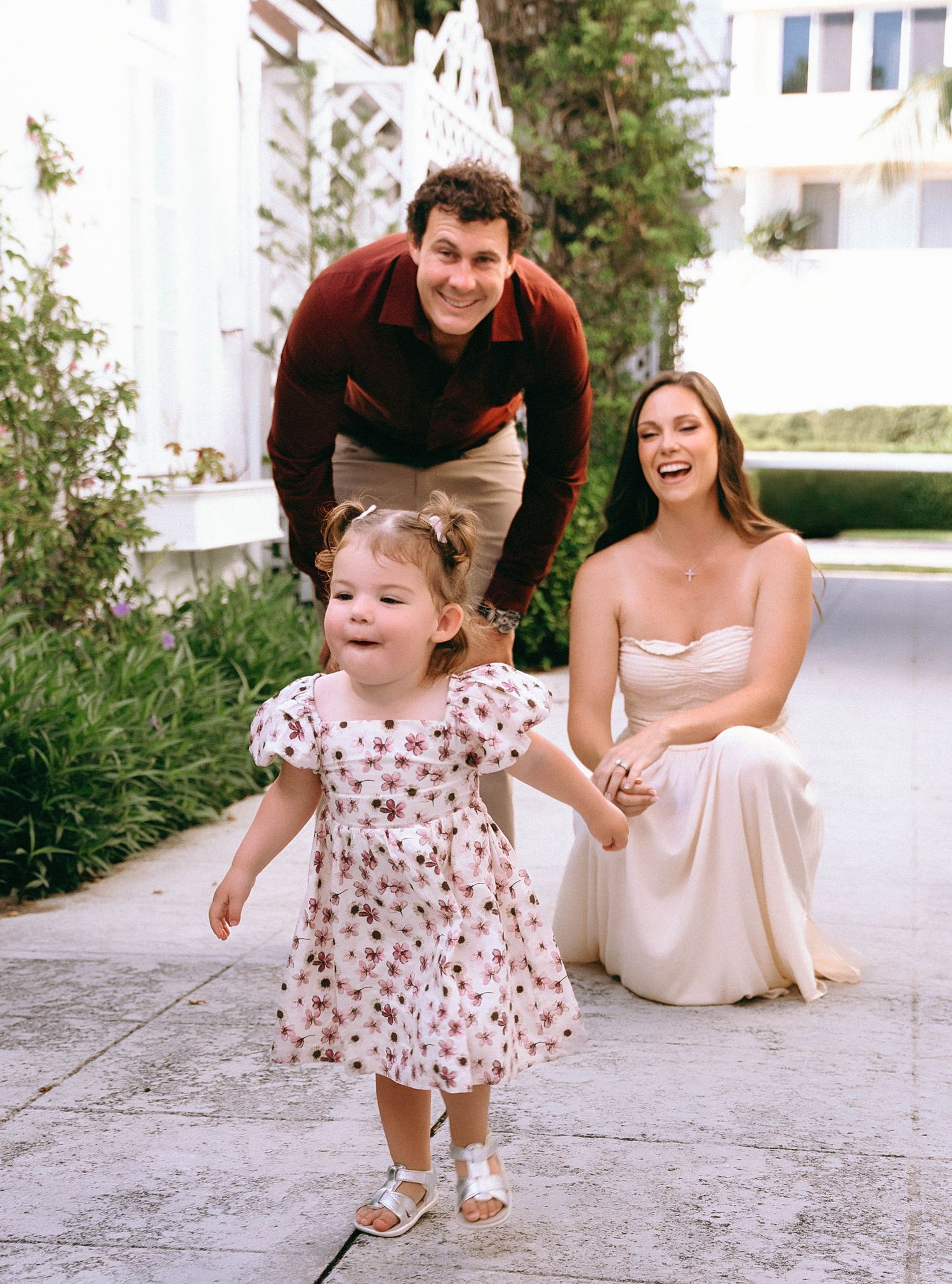 A joyful family moment captured outdoors with a floral dress and light colored outfits.