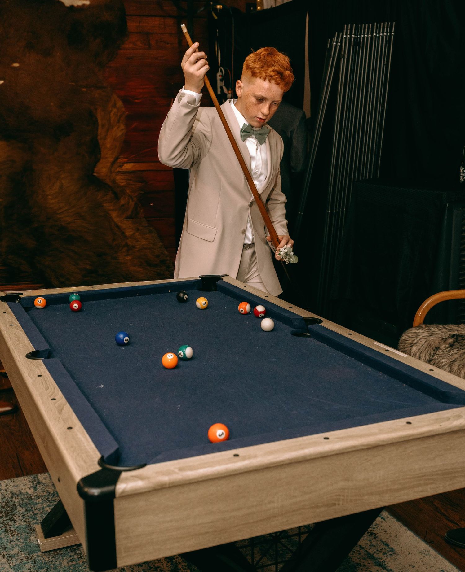 A person in formal attire plays pool on a blue-felted table in a dimly lit room with multiple action shots shown.