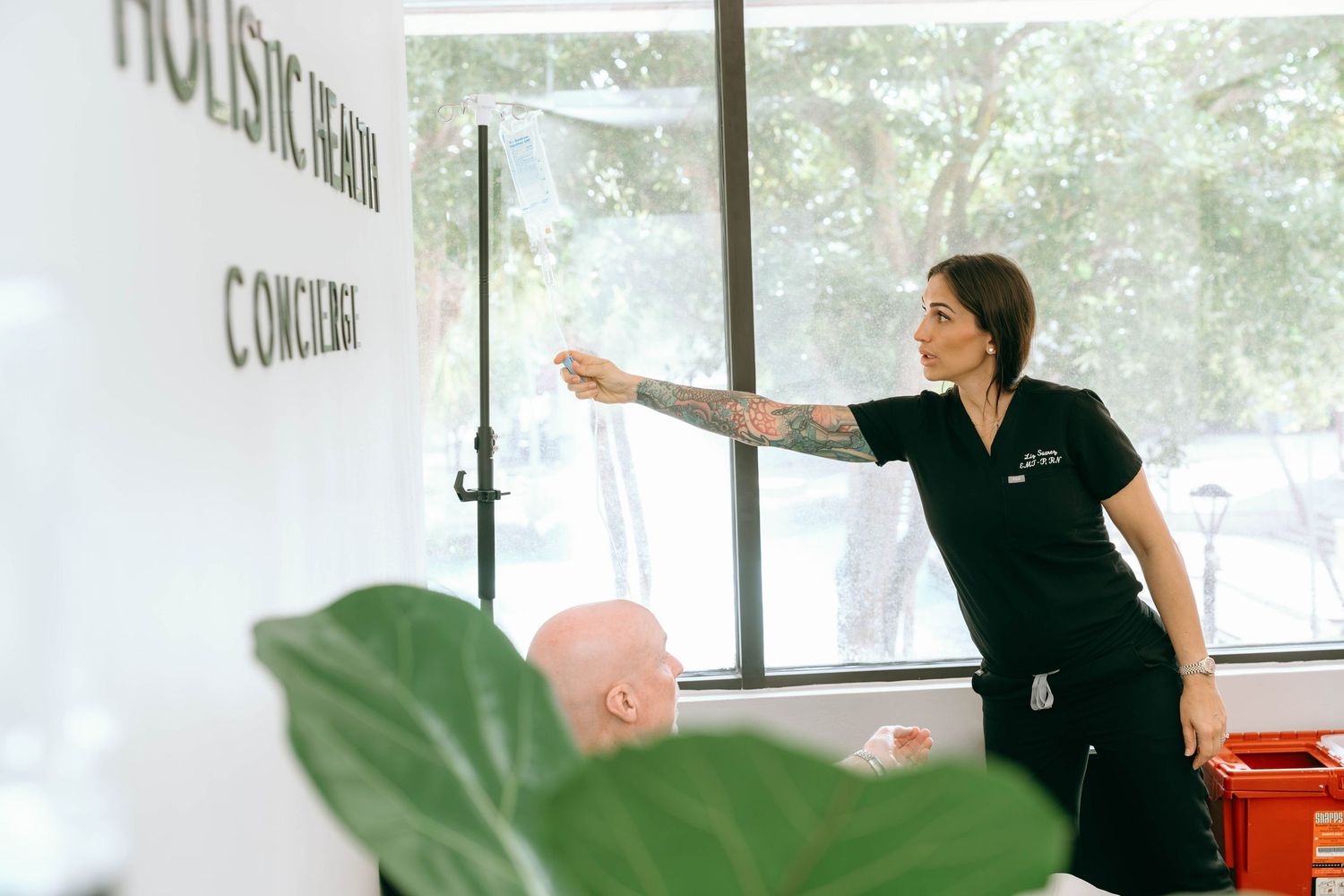 Tattooed female health professional presenting at a holistic health concierge wellness clinic.