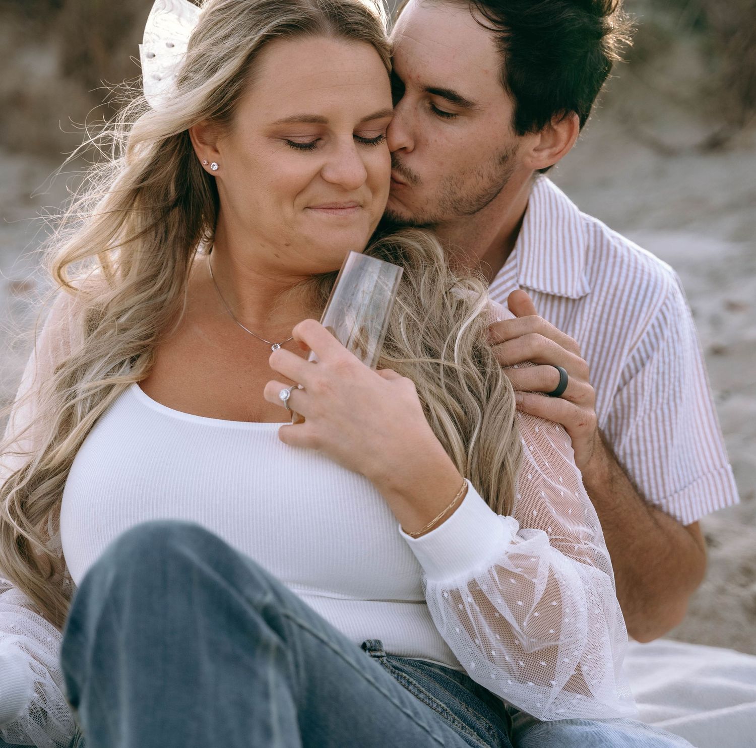 A romantic couple shares an intimate moment against a soft, natural background.