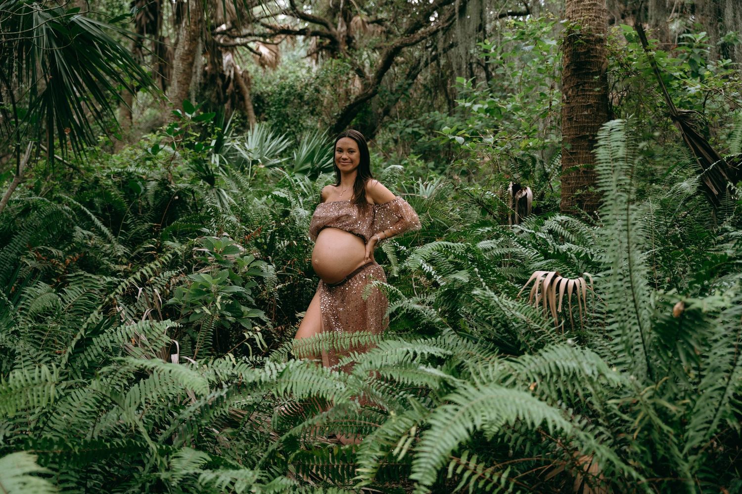 A nature-inspired maternity session among lush ferns and tropical foliage.