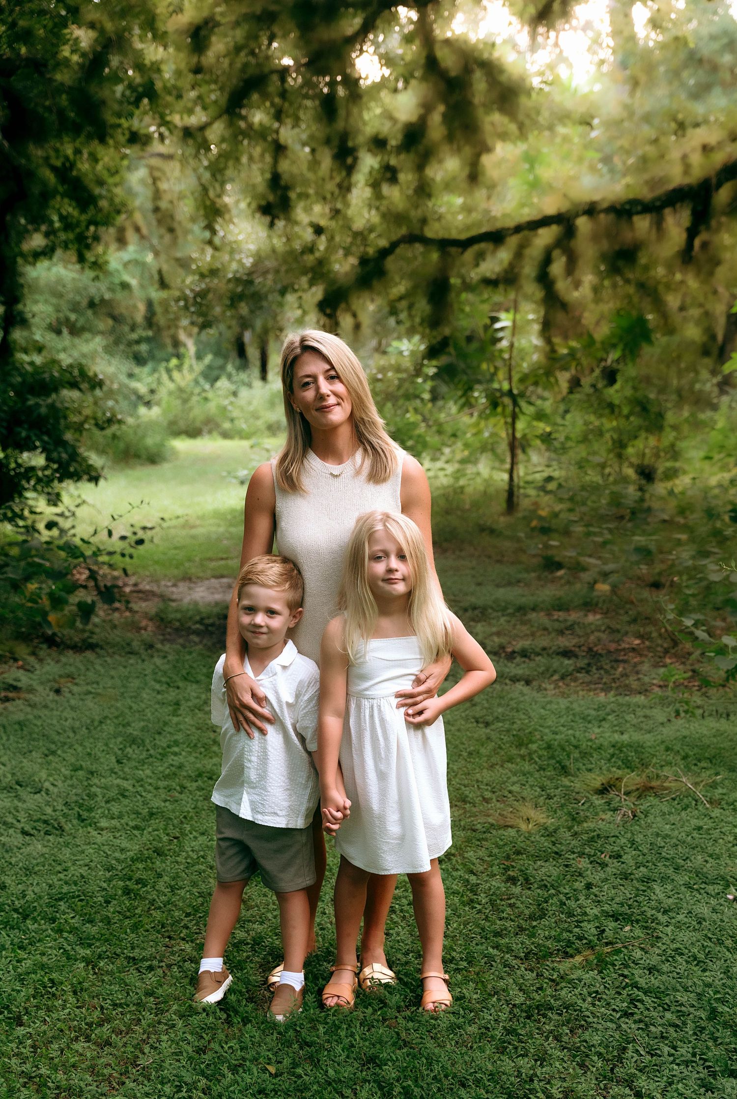 Family portrait in white outfits against a verdant garden backdrop.
