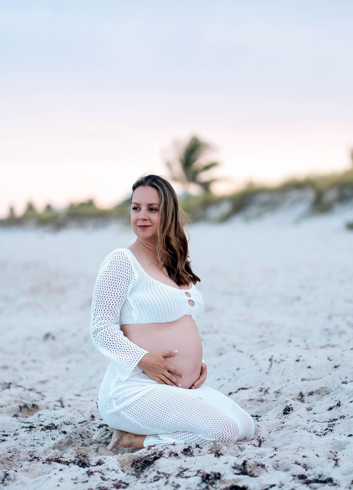 Maternity photos on white sandy beach at sunset.