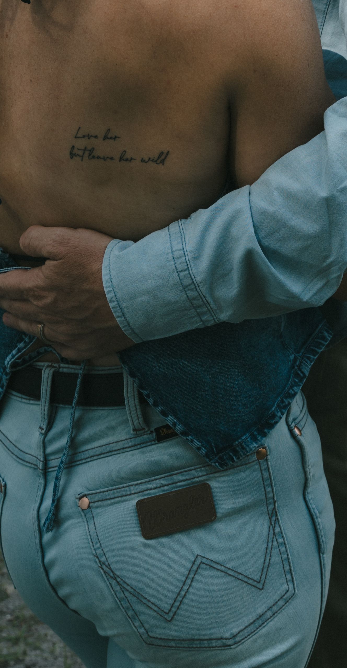Close-up of denim jeans pockets and belt loops in natural lighting.