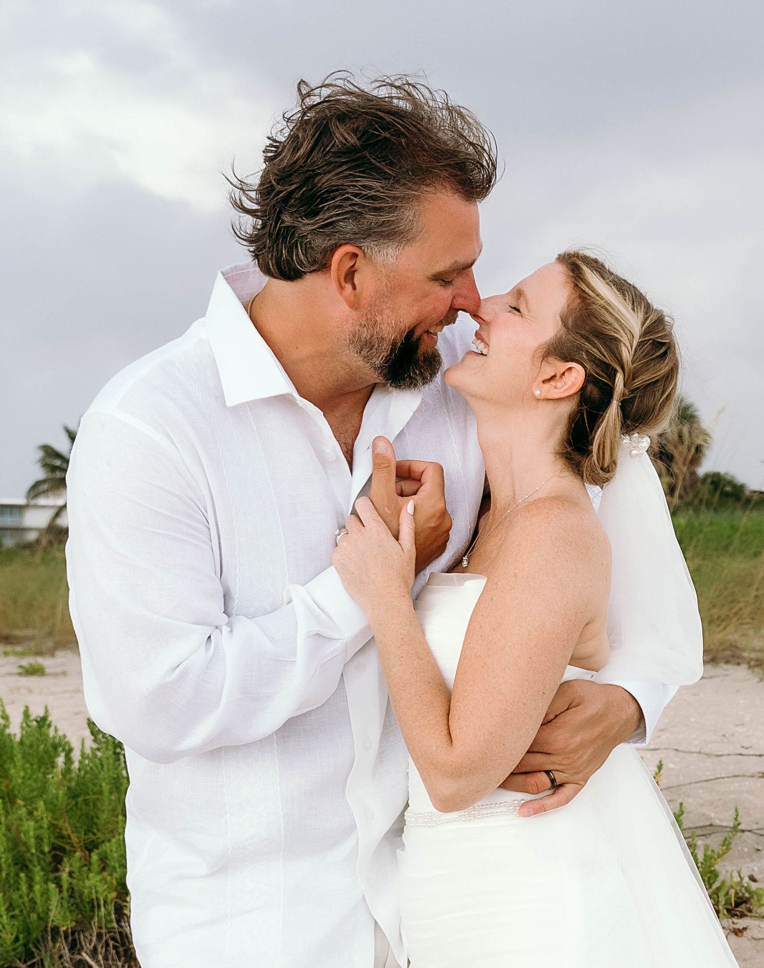 A romantic beach wedding photoshoot sequence showing tender moments between a couple in white attire.