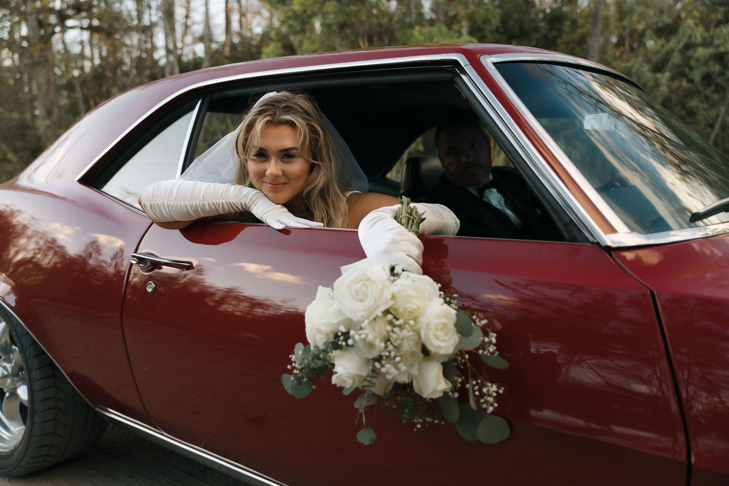 Classic red vintage car decorated with white flowers for a wedding celebration.