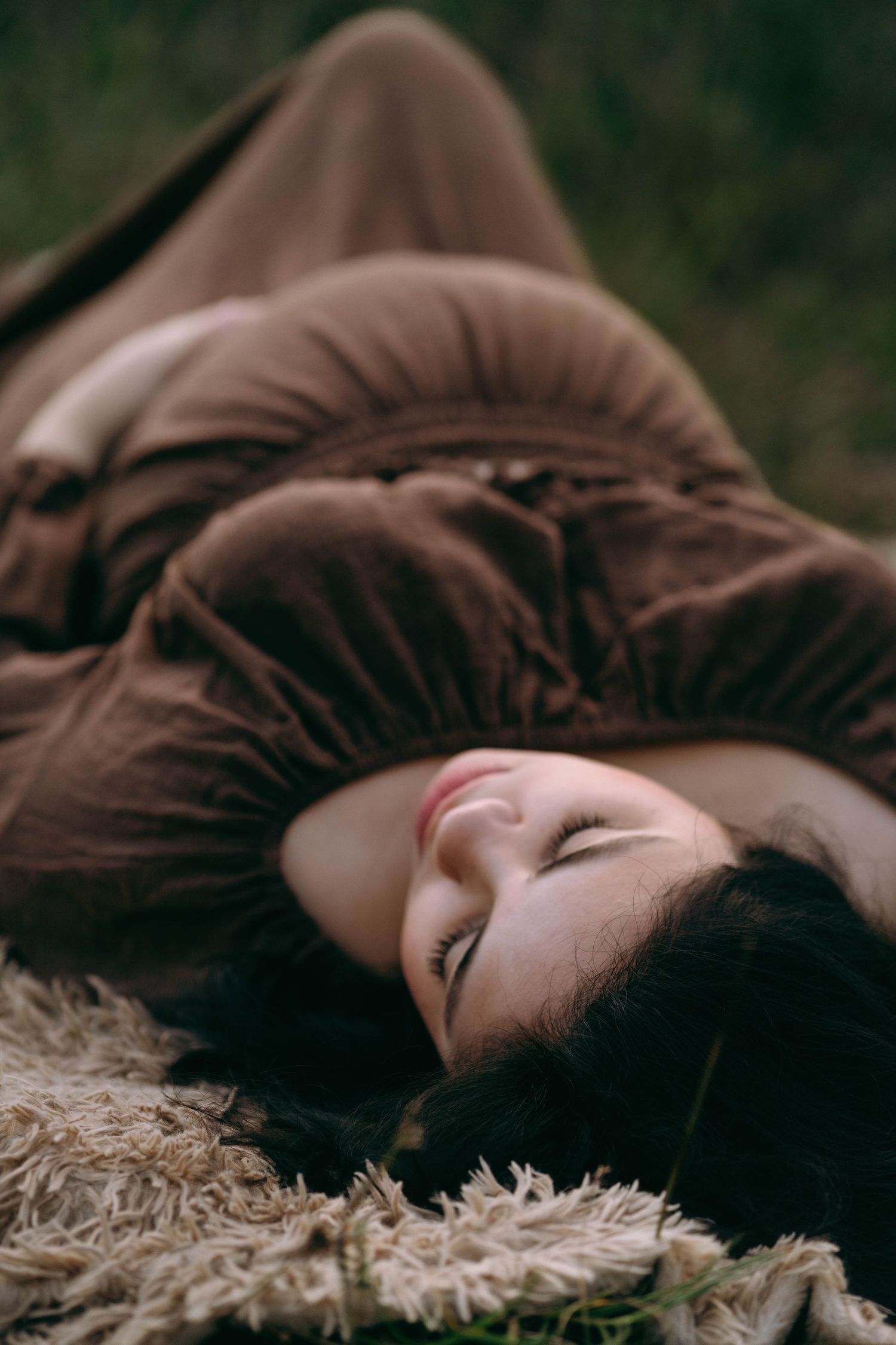 Artistic portrait of a person lying on a textured white surface with dark hair flowing.