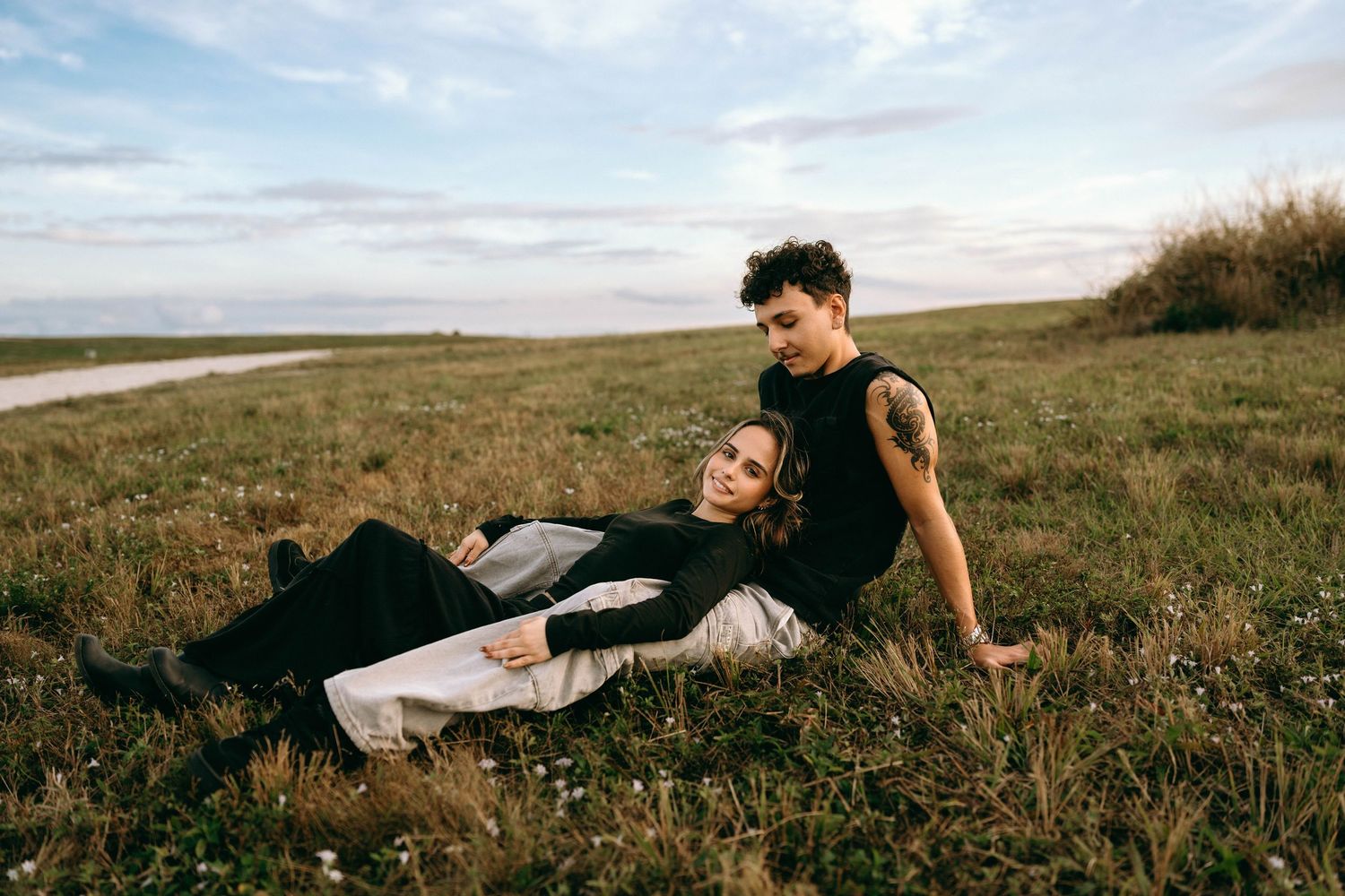 Couple relaxing together in flowering meadow during outdoor photoshoot.
