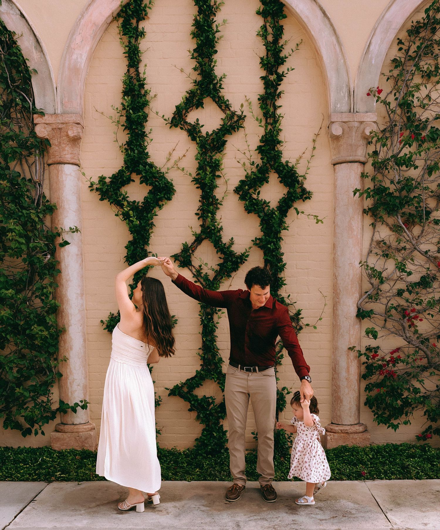 A playful family pose against an ivy-covered archway wall outdoors.